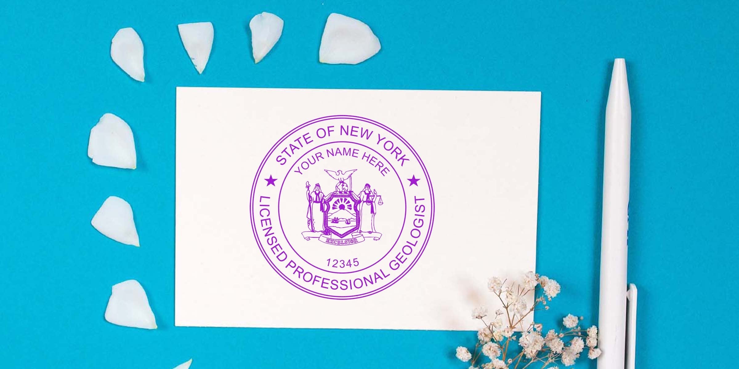 New York licensed geologist stamp design on white card, with pen and flower petals on blue background.
