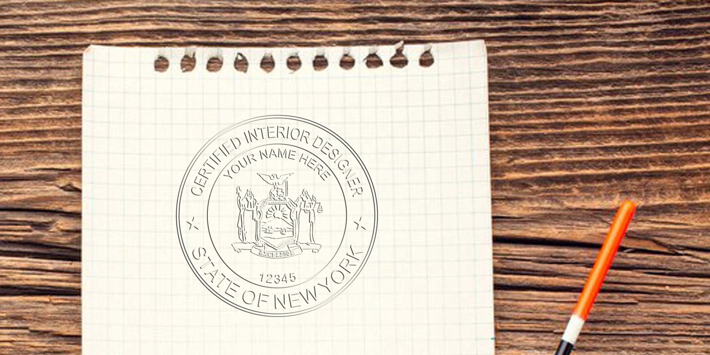 New York interior designer seal stamped on graph paper with orange pen on wooden table, displaying NY interior design certification.