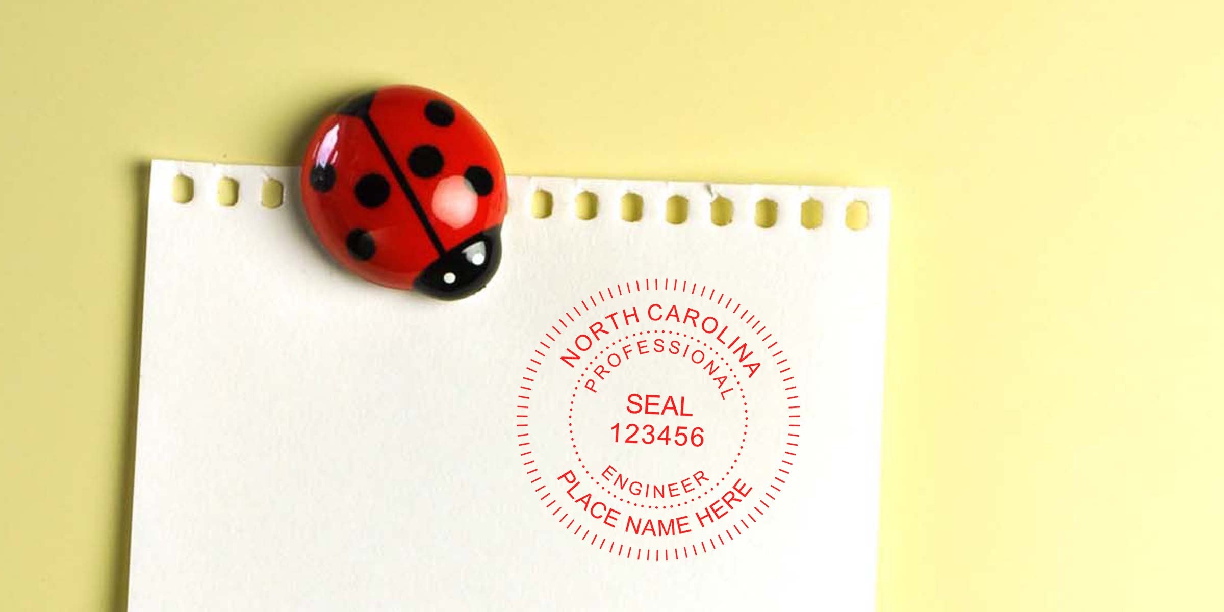 North Carolina engineer seal on white paper with ladybug magnet on yellow background, illustrating NC engineer stamp laws and project compliance.