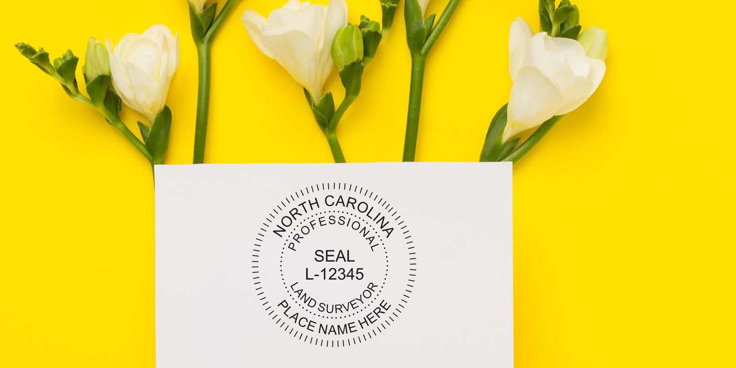 North Carolina land surveyor stamp on white paper, framed by white flowers, set against a bright yellow background, highlighting the stamp's details.
