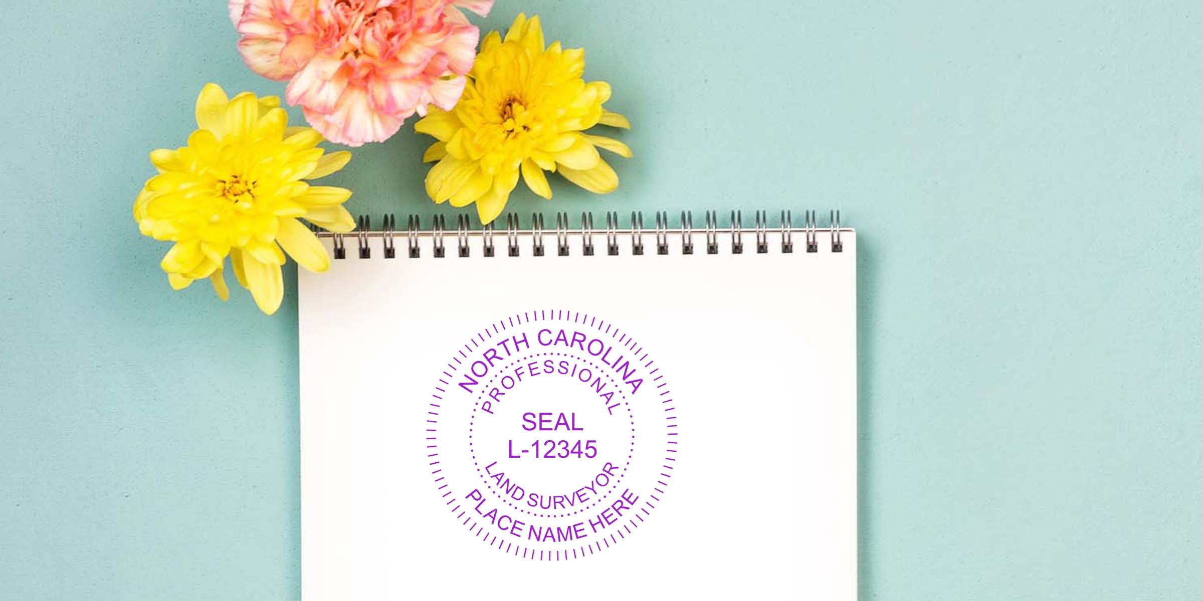 North Carolina surveyor stamp on white notepad with yellow and pink flowers against a blue background, showcasing a professional self-inking stamp design.