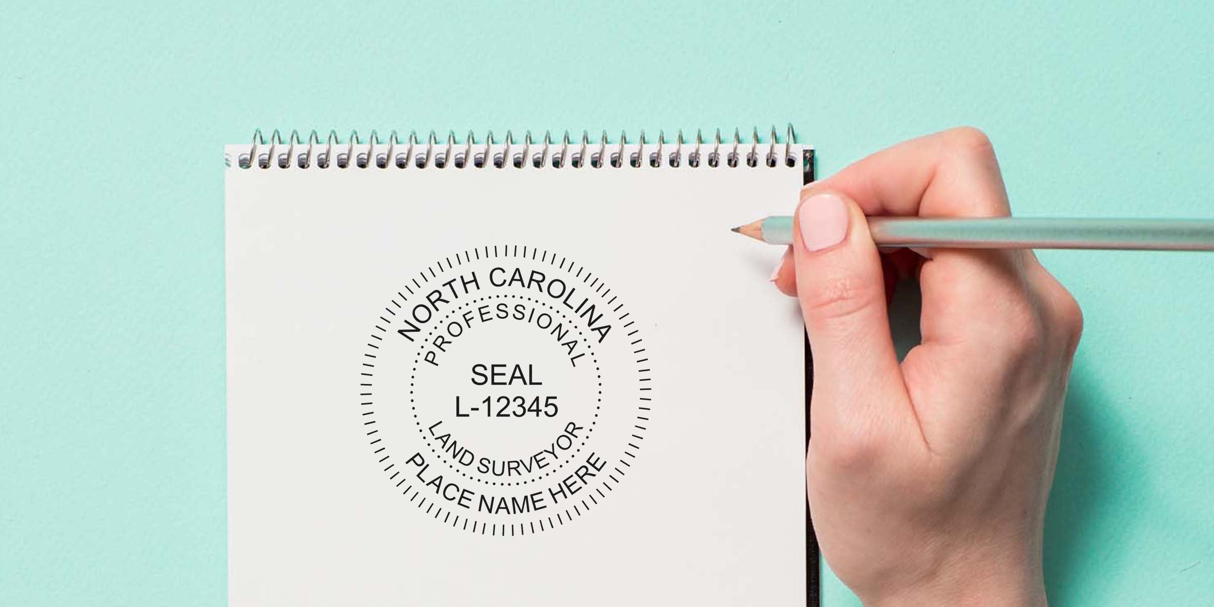 North Carolina professional land surveyor seal on white notepad with hand holding pencil, showing NC surveyor stamp and its requirements.