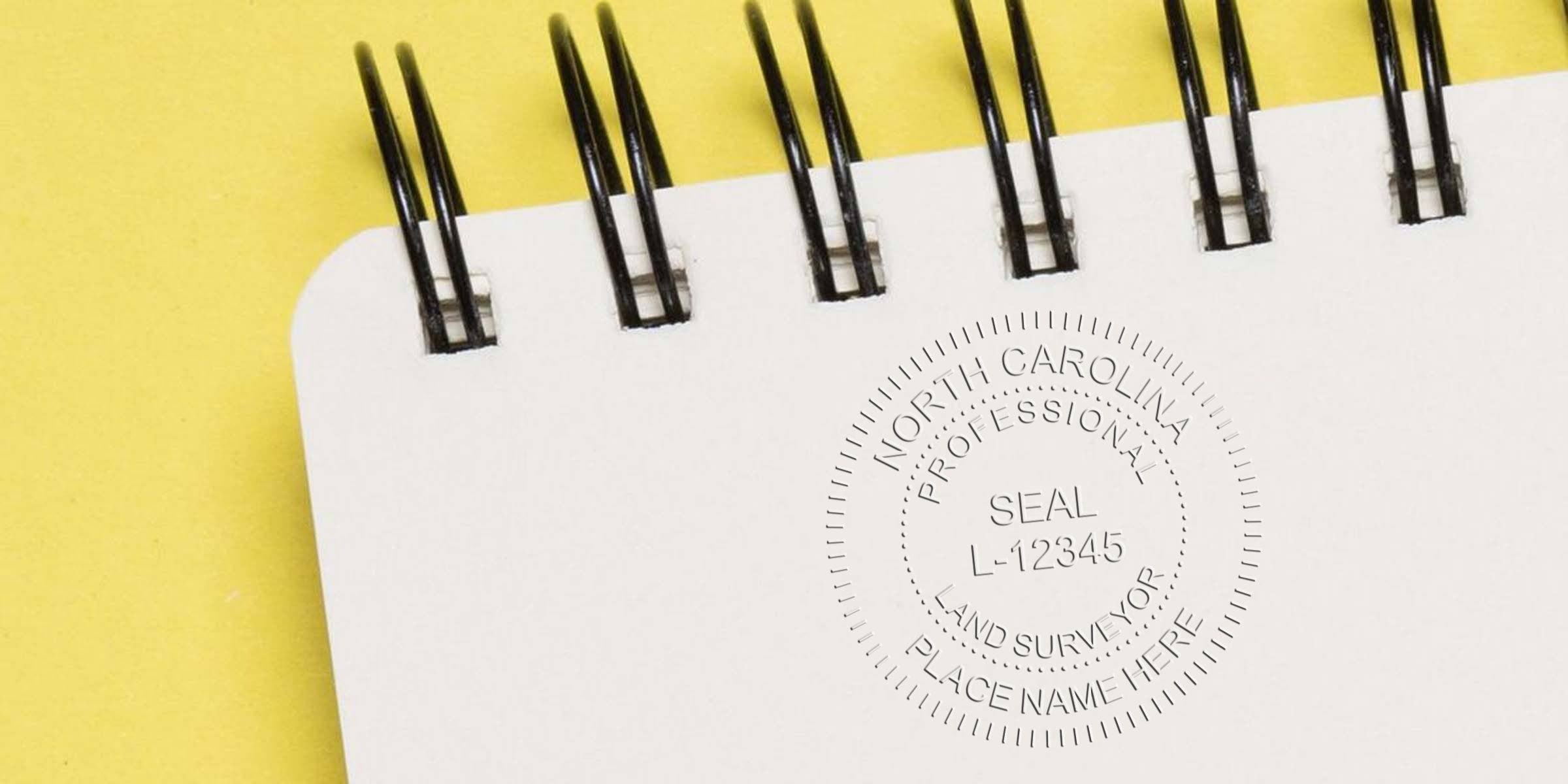 Embossed North Carolina surveyor seal on white spiral notebook with yellow background, showcasing professional land surveyor design and promoting online surveyor seal purchase.