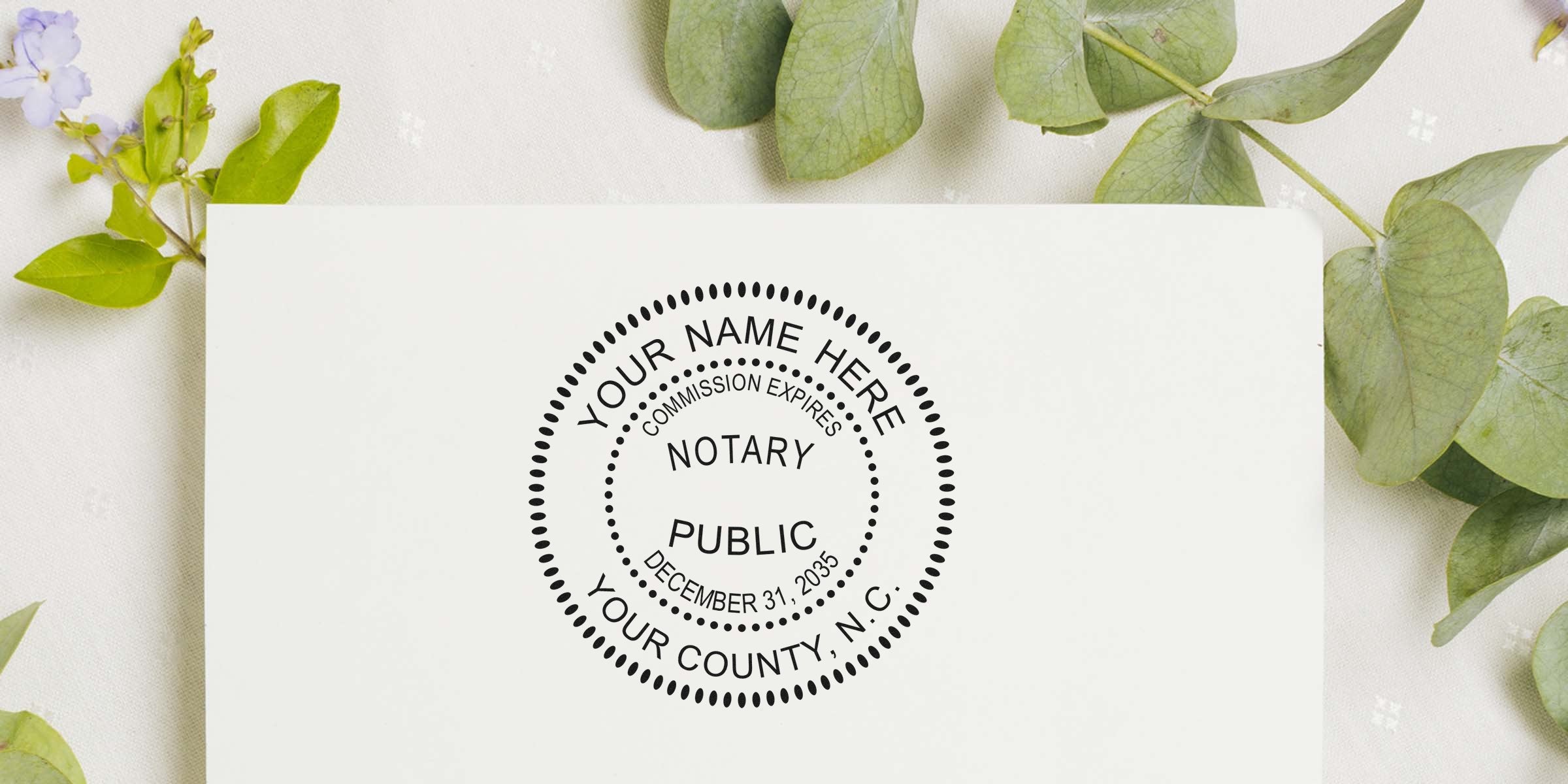 Notary public stamp with commission expiration date on white paper, surrounded by green leaves, highlighting NC notary supplies and new essentials.