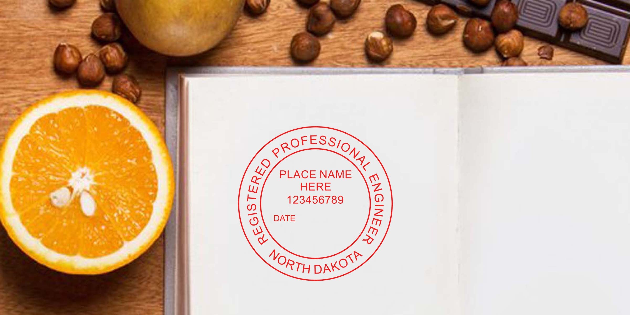 Open notebook with North Dakota engineering seals and registered engineer stamp, surrounded by orange slice, hazelnuts, and chocolate on wooden table, displaying engineering seal design options.