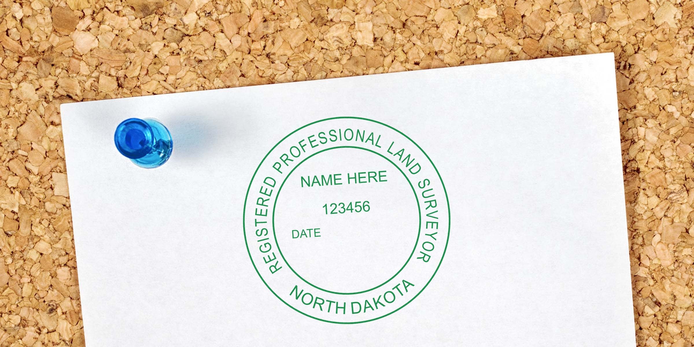 Registered professional land surveyor stamp from North Dakota on white paper pinned to a corkboard, showing a self-inking surveyor stamp design.