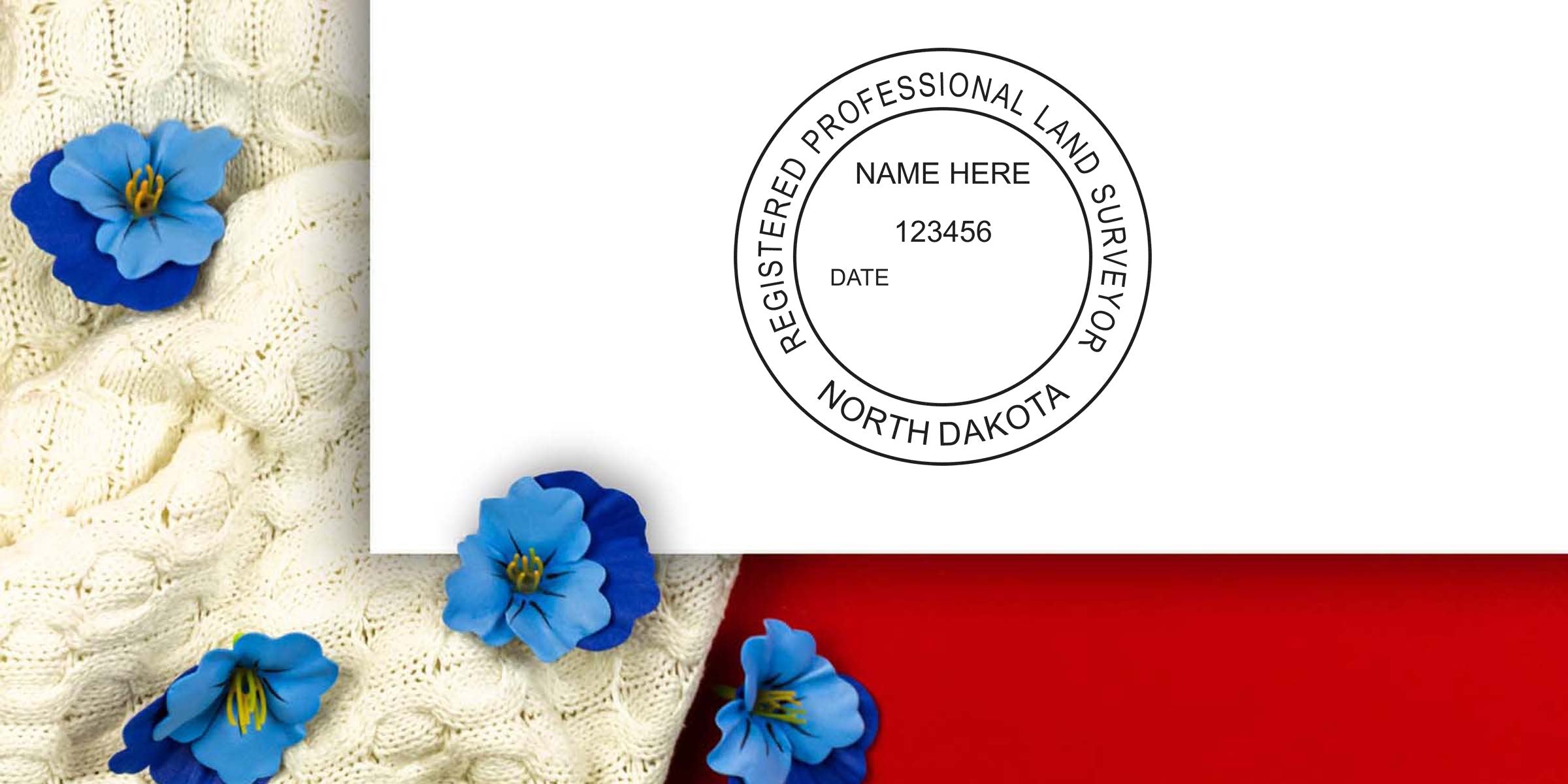 North Dakota land surveyor seal stamped on white paper, showing the official design, placed on knitted fabric with blue flowers and a red background.