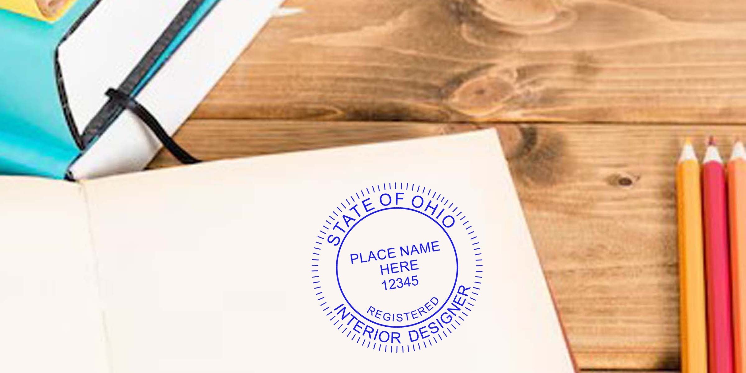 Ohio interior designer seal stamped on notebook, with colored pencils and planner on wooden desk, symbolizing Ohio interior design certification.