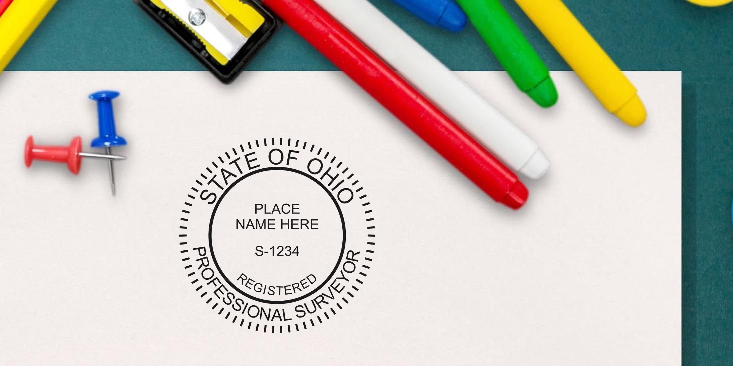 Ohio land surveyor stamp on white paper, surrounded by colorful markers and push pins, emphasizing Ohio land surveyor stamp and land surveyor requirements in Ohio.