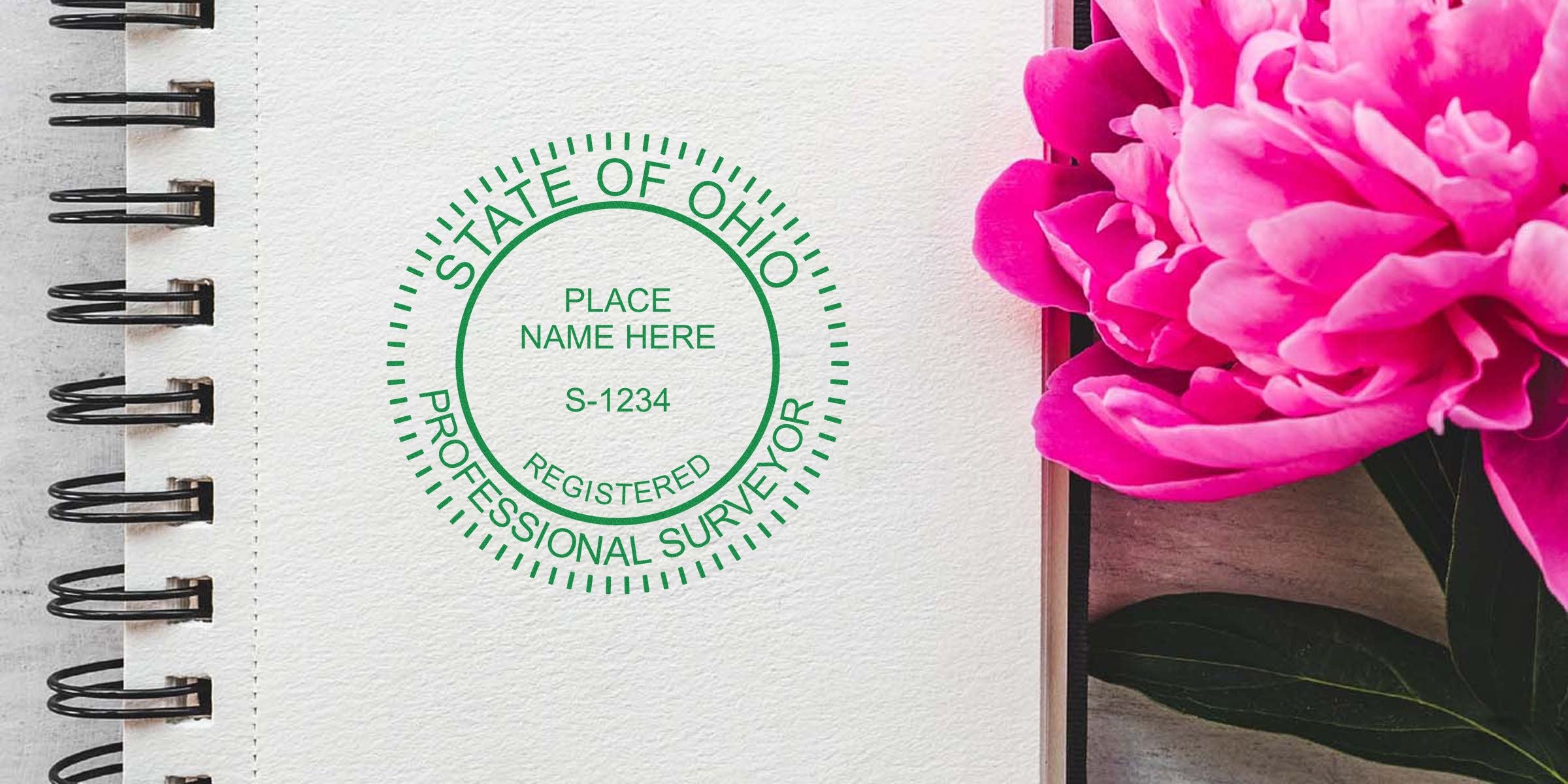 Ohio land surveyor seal stamped on notebook beside pink peony, symbolizing land surveying services and adherence to Ohio land surveyor regulations.