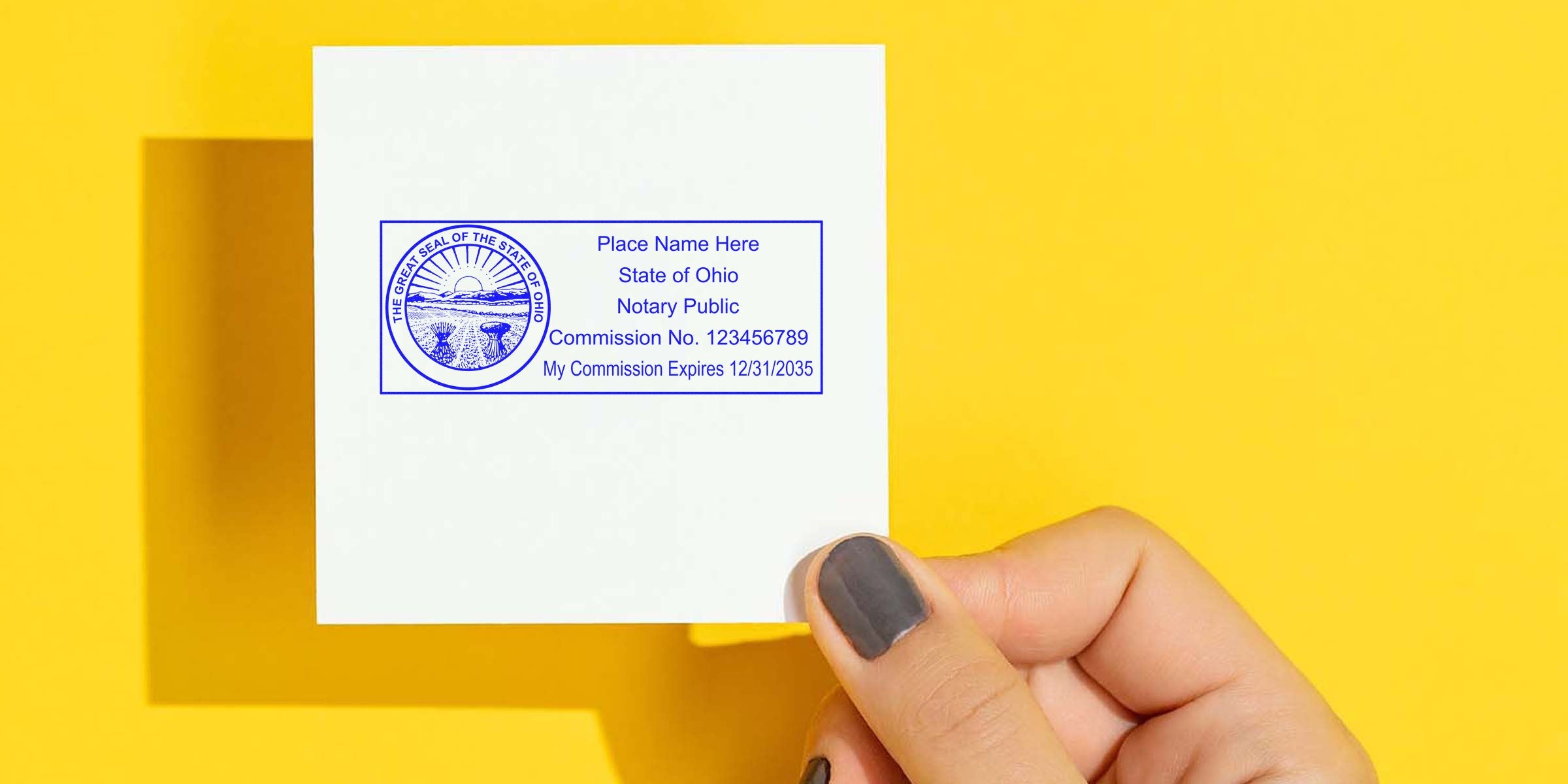 Hand holding Ohio notary public stamp on white paper with yellow background, showing Ohio notary seal and online notary services in Ohio.