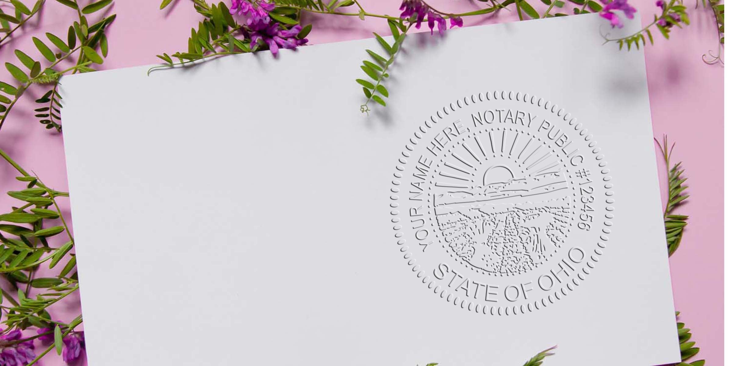 Ohio notary embossed seal on white paper with purple flowers and green leaves, set against a pink background, showcasing trusted notary supplies.