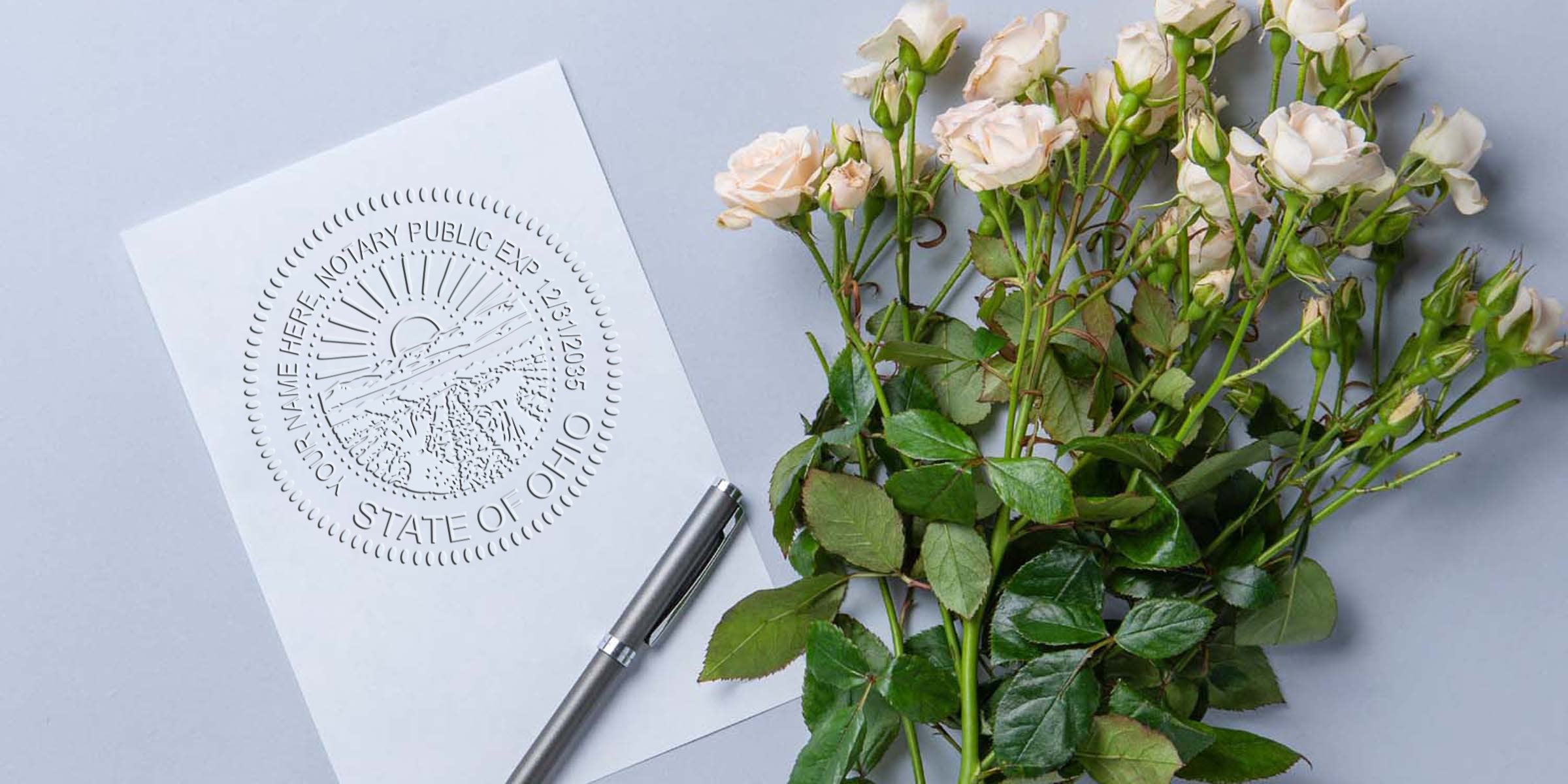 Ohio notary public embossed seal on white paper with silver pen and white rose bouquet on gray background, symbolizing Ohio Notary Stamp Renewal and Renewal Requirements.
