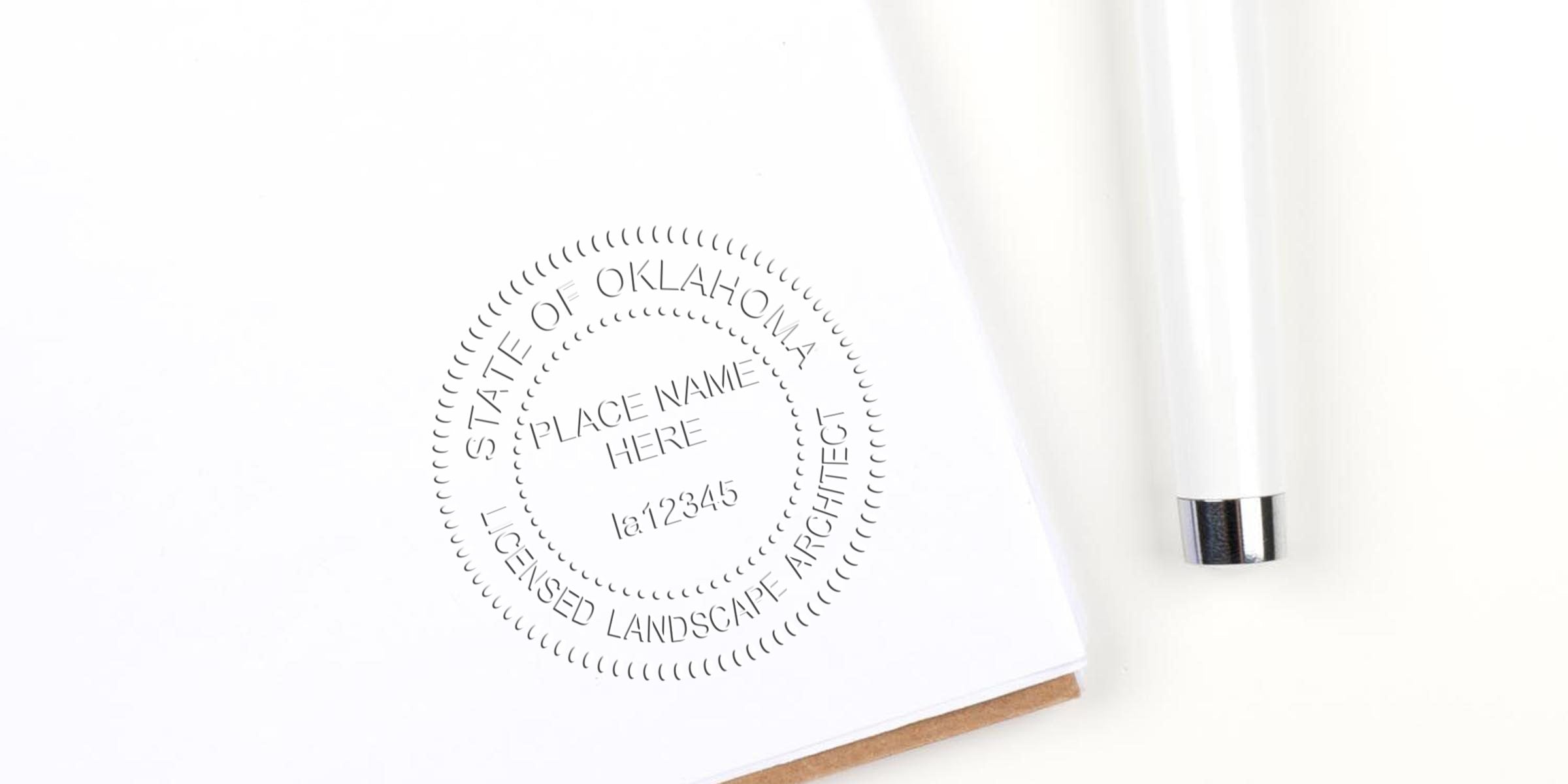 Embossed Oklahoma licensed landscape architect seal on white paper with white pen, showing the state stamp and referencing landscape architect licensing requirements.