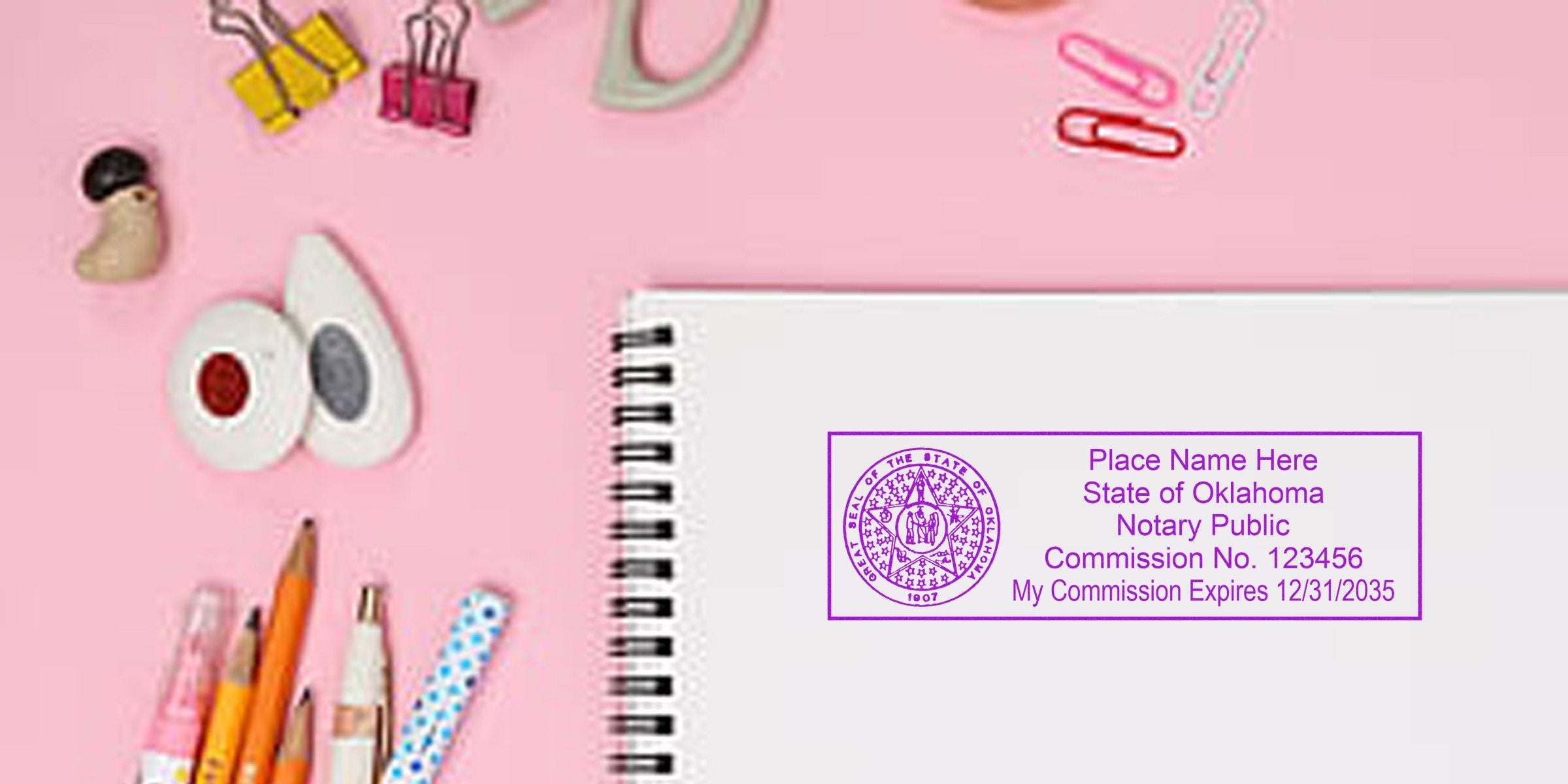Oklahoma notary seal on notebook with office supplies on a pink background. Purchase your Oklahoma notary seal today.