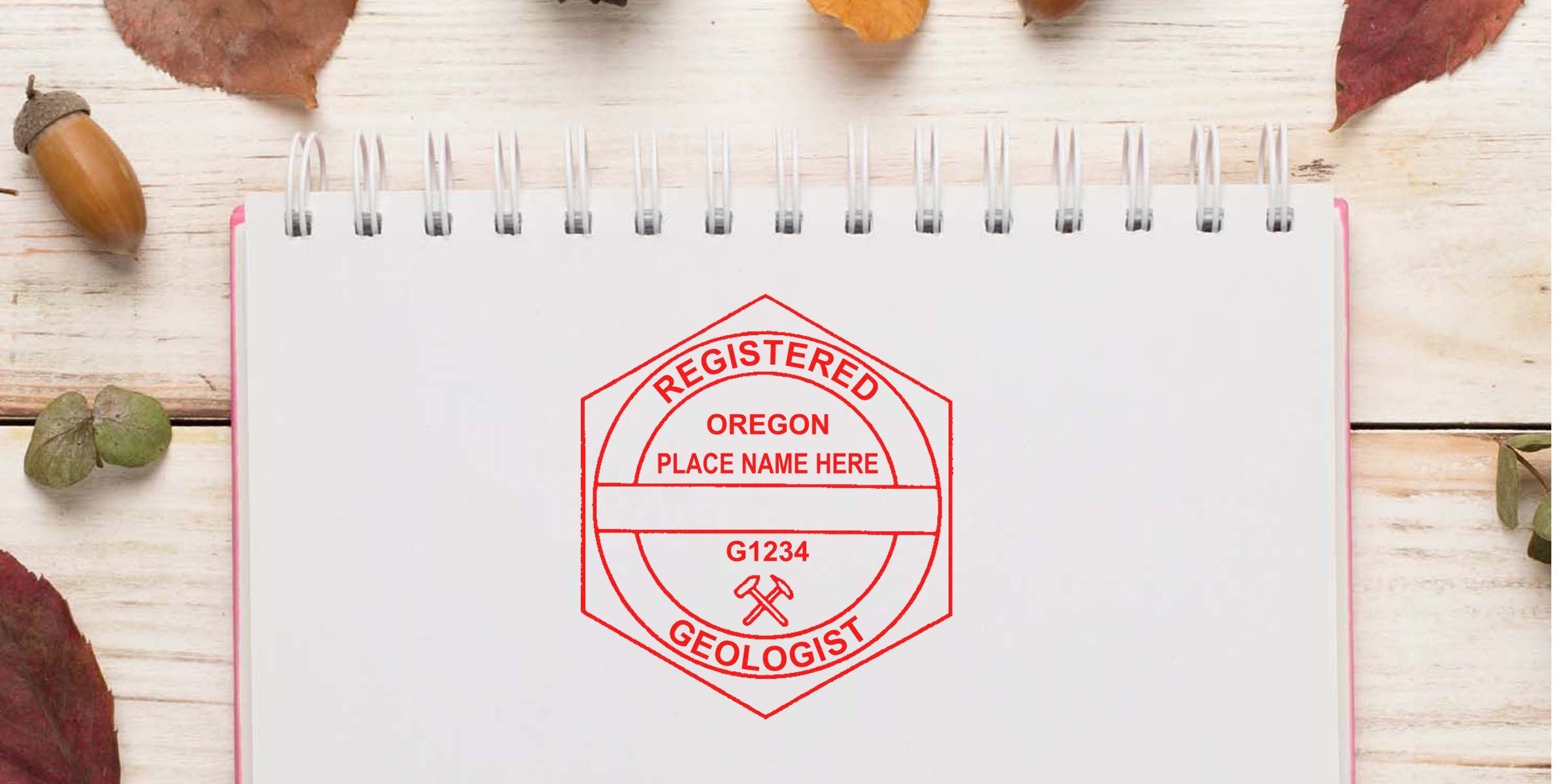 Oregon Geologist Seal stamp on notebook with Geology Badge design, autumn leaves, and acorn background.