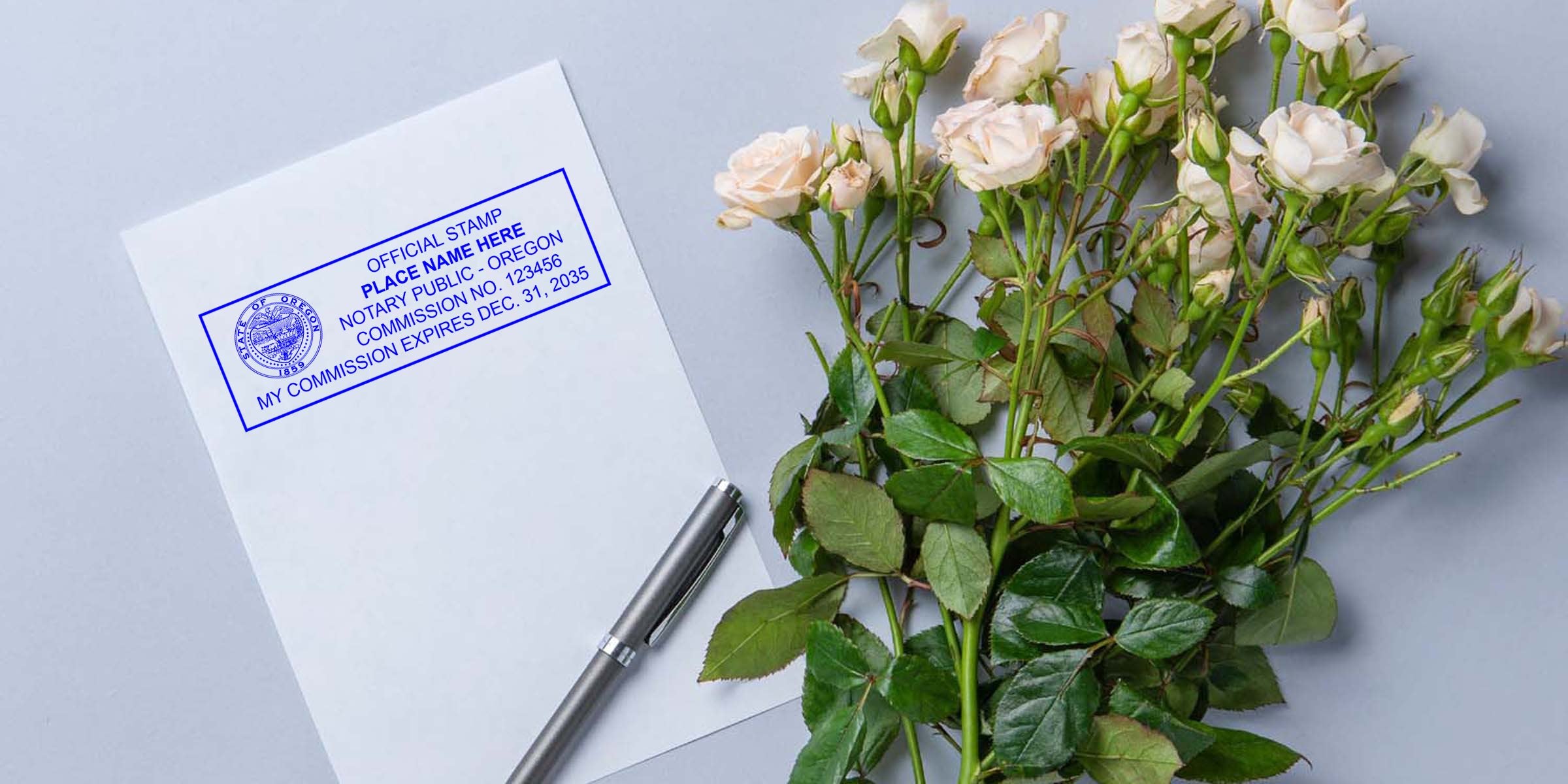 Oregon notary stamp on paper with pen and white rose on gray background, emphasizing the value of investing in quality notary tools.