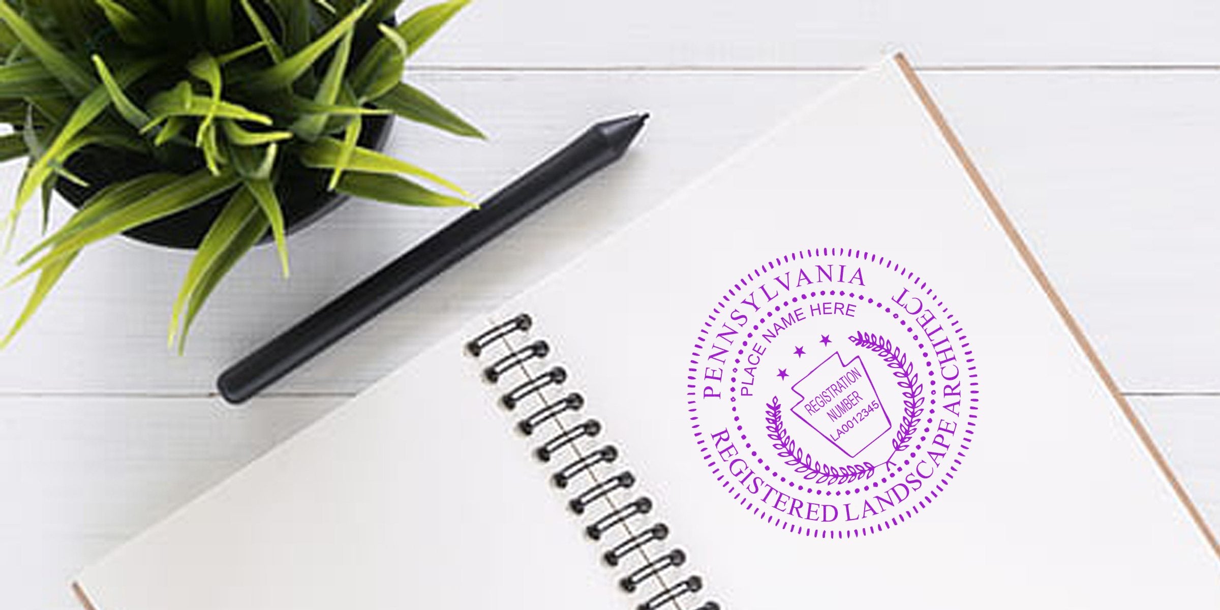 Pennsylvania-registered landscape architect stamp on notebook with pen and plant on white wooden desk, meeting PA embosser standards.