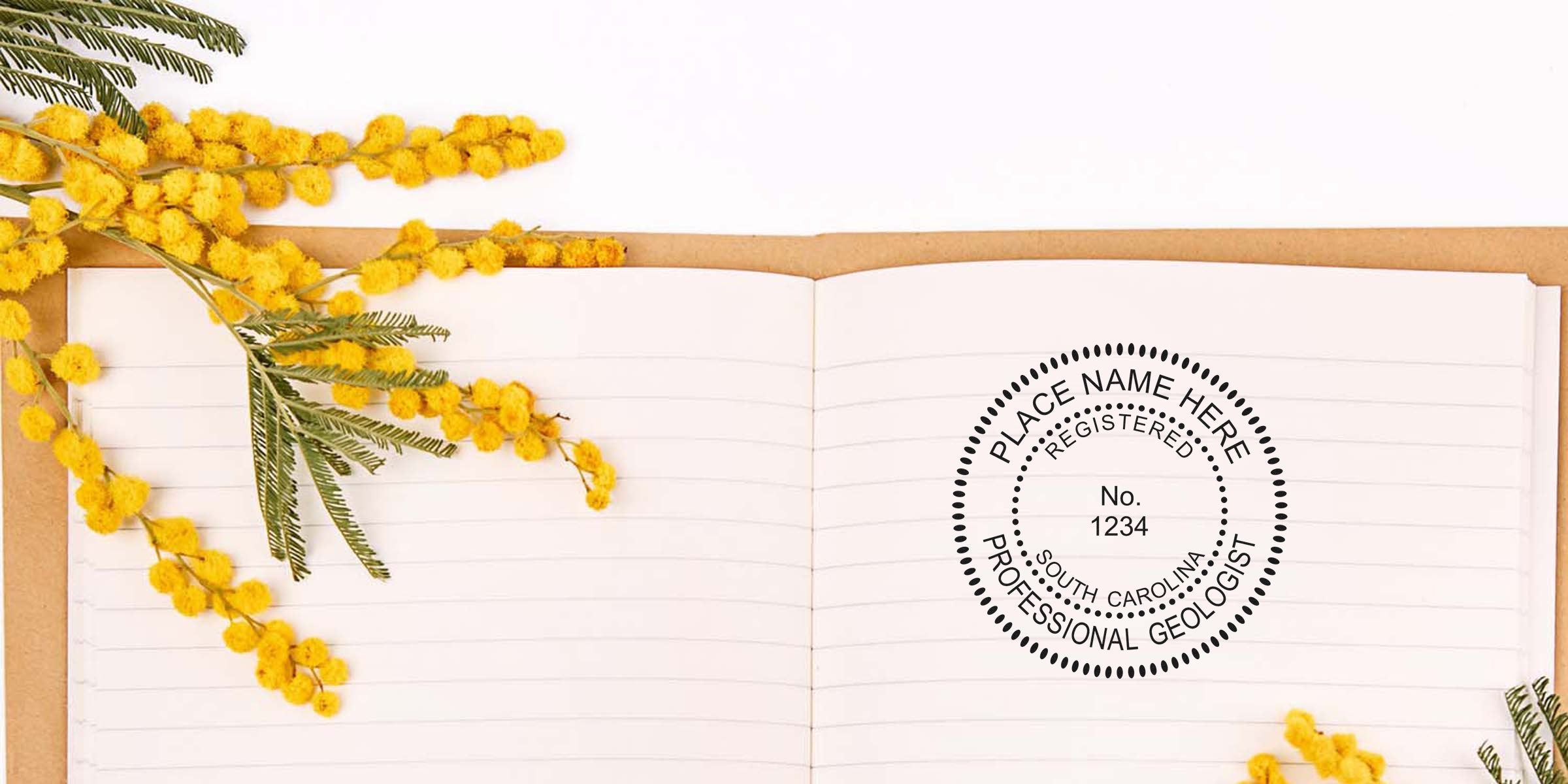 Open notebook with yellow mimosa flowers and an affordable South Carolina professional geologist stamp on white, highlighting the cost of the South Carolina geologist stamp.