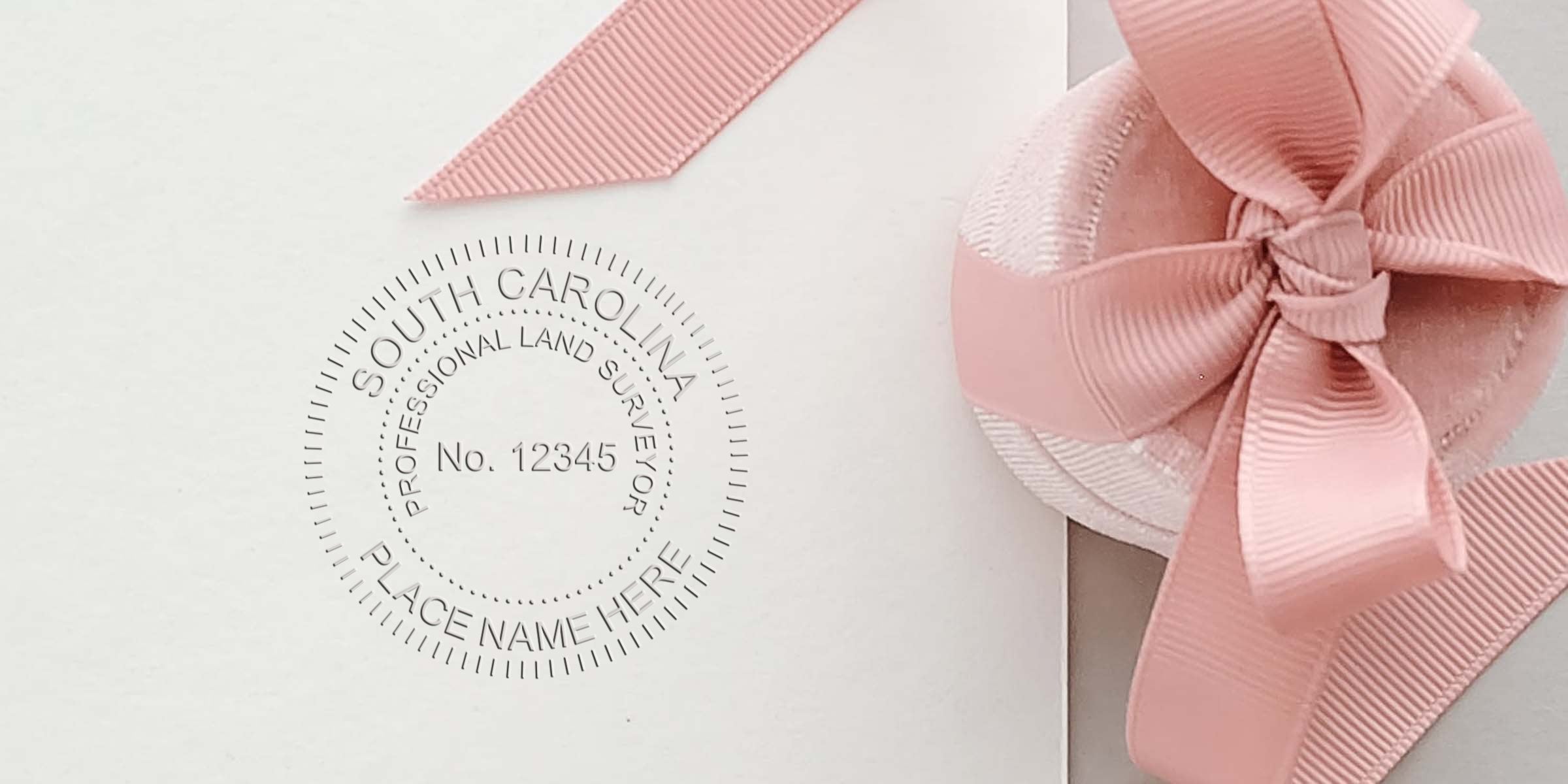 South Carolina land surveyor seal embossed on white paper with pink ribbon bow, complying with all South Carolina land surveyor seal requirements.