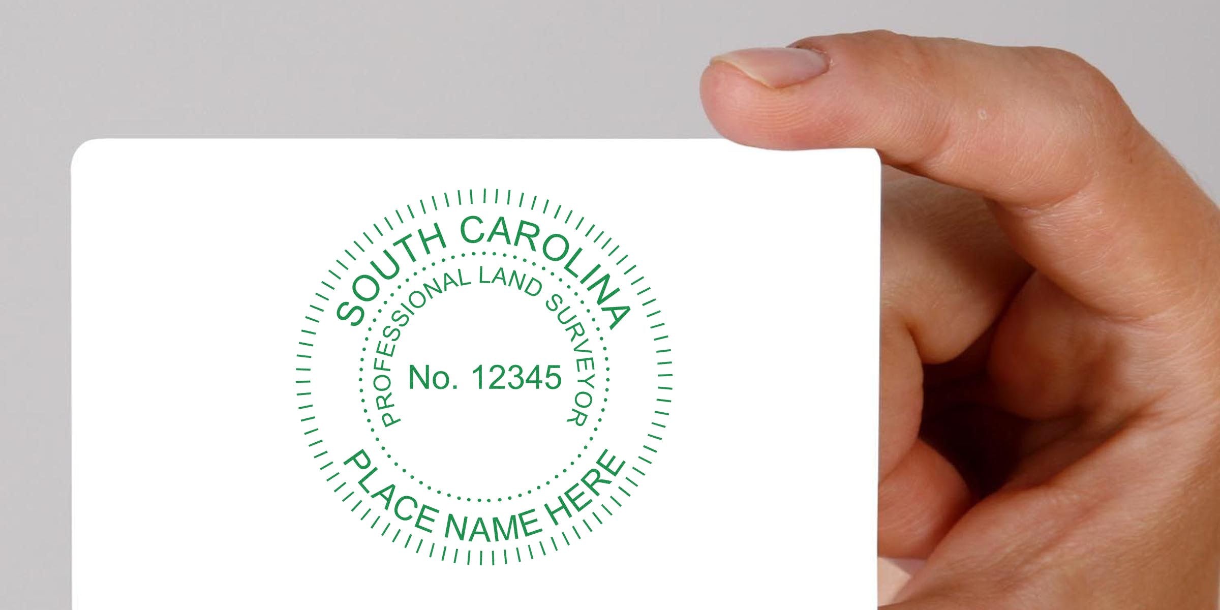 South Carolina land surveyor seal stamp with seal design on white card held by hand.