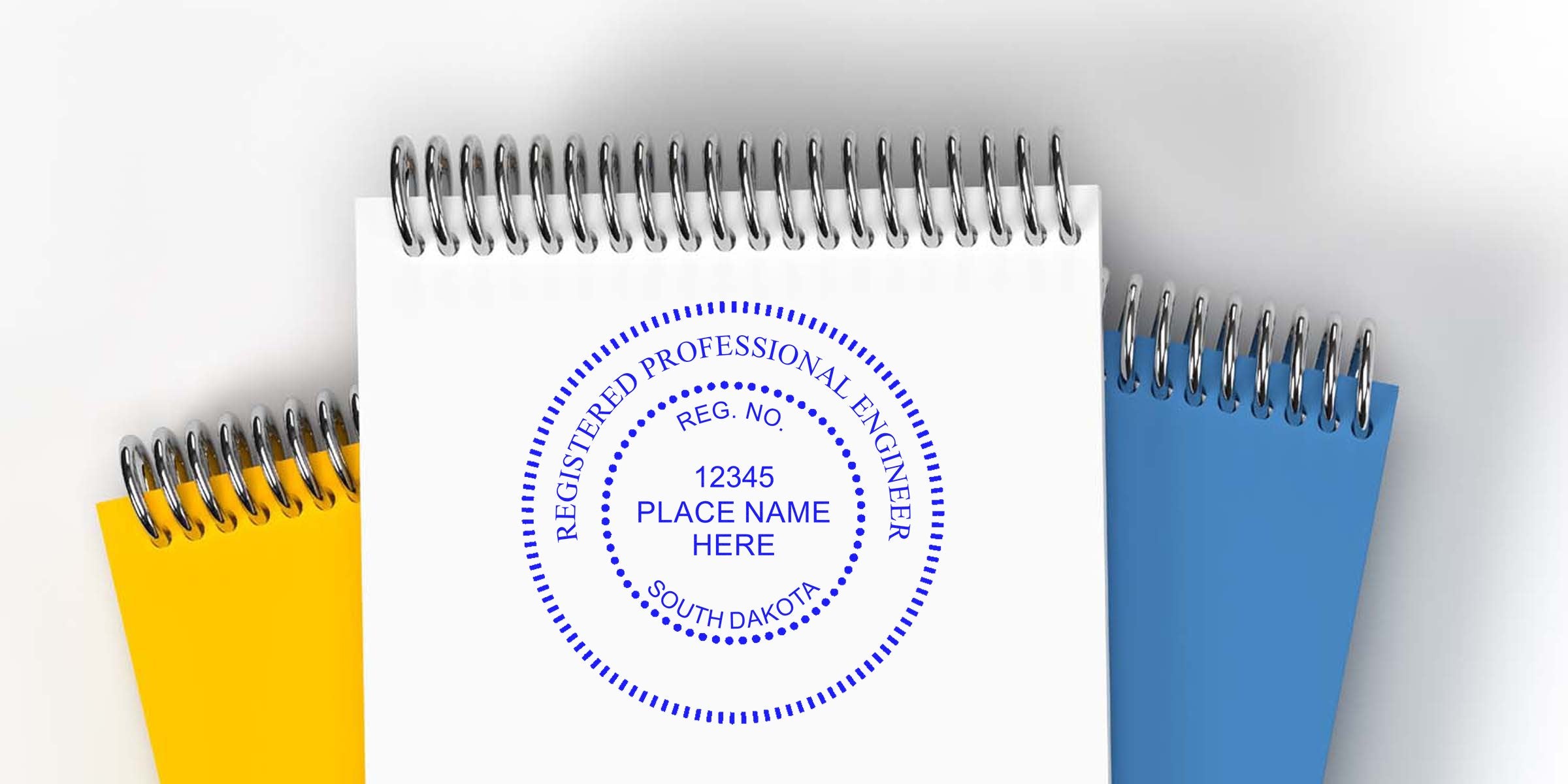 Registered professional engineer stamp on white notebook with South Dakota engineer seal, highlighting SD PE Seal rules and licensing, with yellow and blue notebooks in the background.