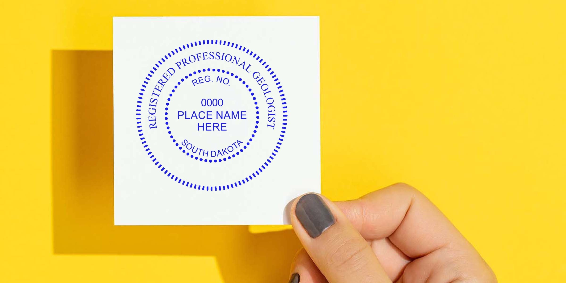 Hand holding white paper with South Dakota Geologist Stamp, a registered professional geologist seal, against yellow background, perfect for geologist stamp collectors.