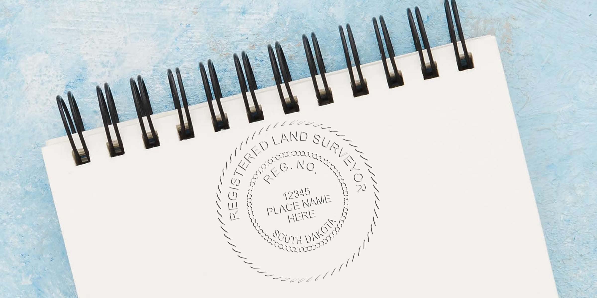 South Dakota land surveyor seal stamped on a white spiral notebook, featuring a professional design for land surveying services in South Dakota.