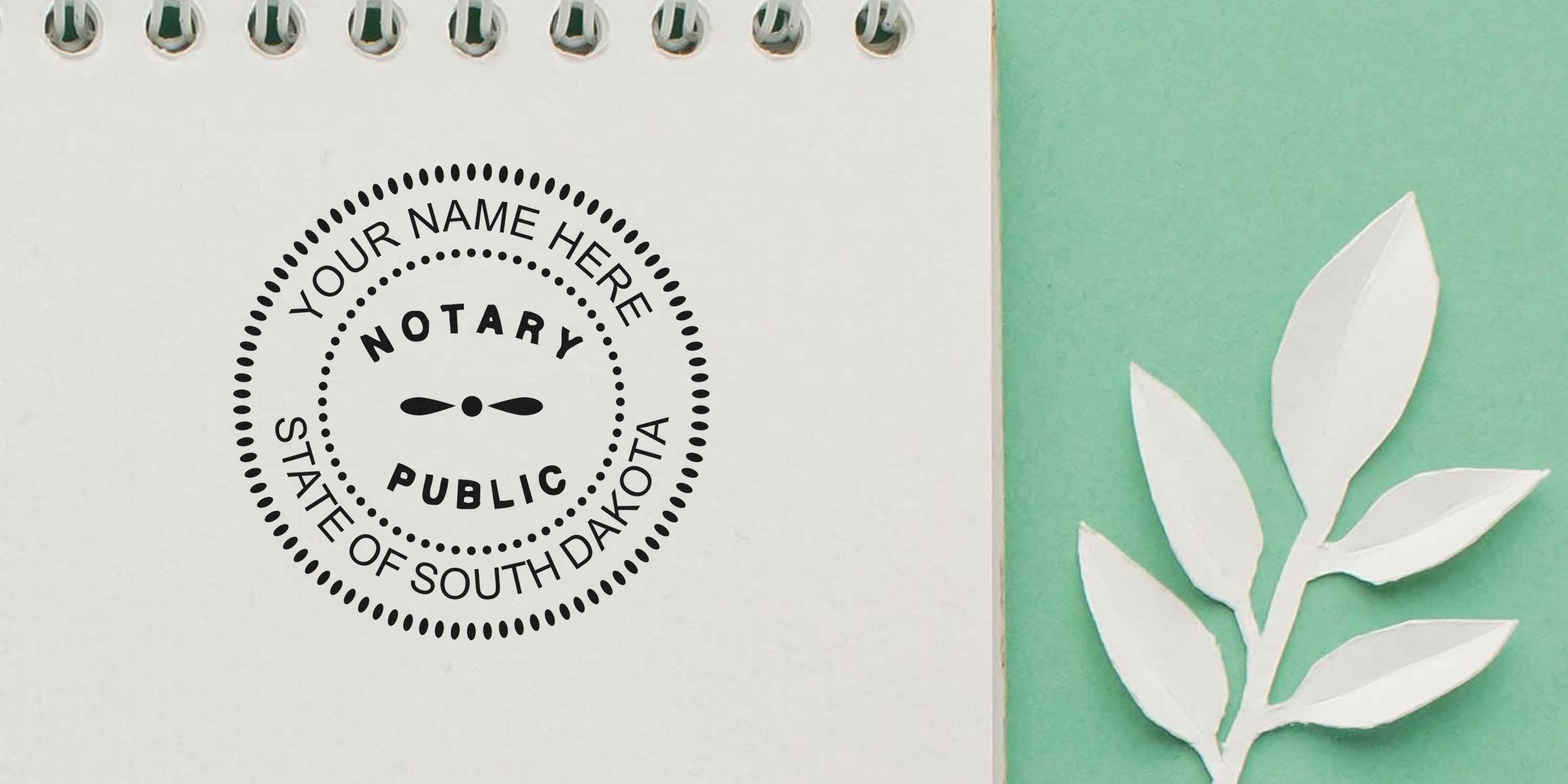 South Dakota notary public seal stamp on white paper, surrounded by decorative white leaves on green background, with South Dakota notary supplies and tools.