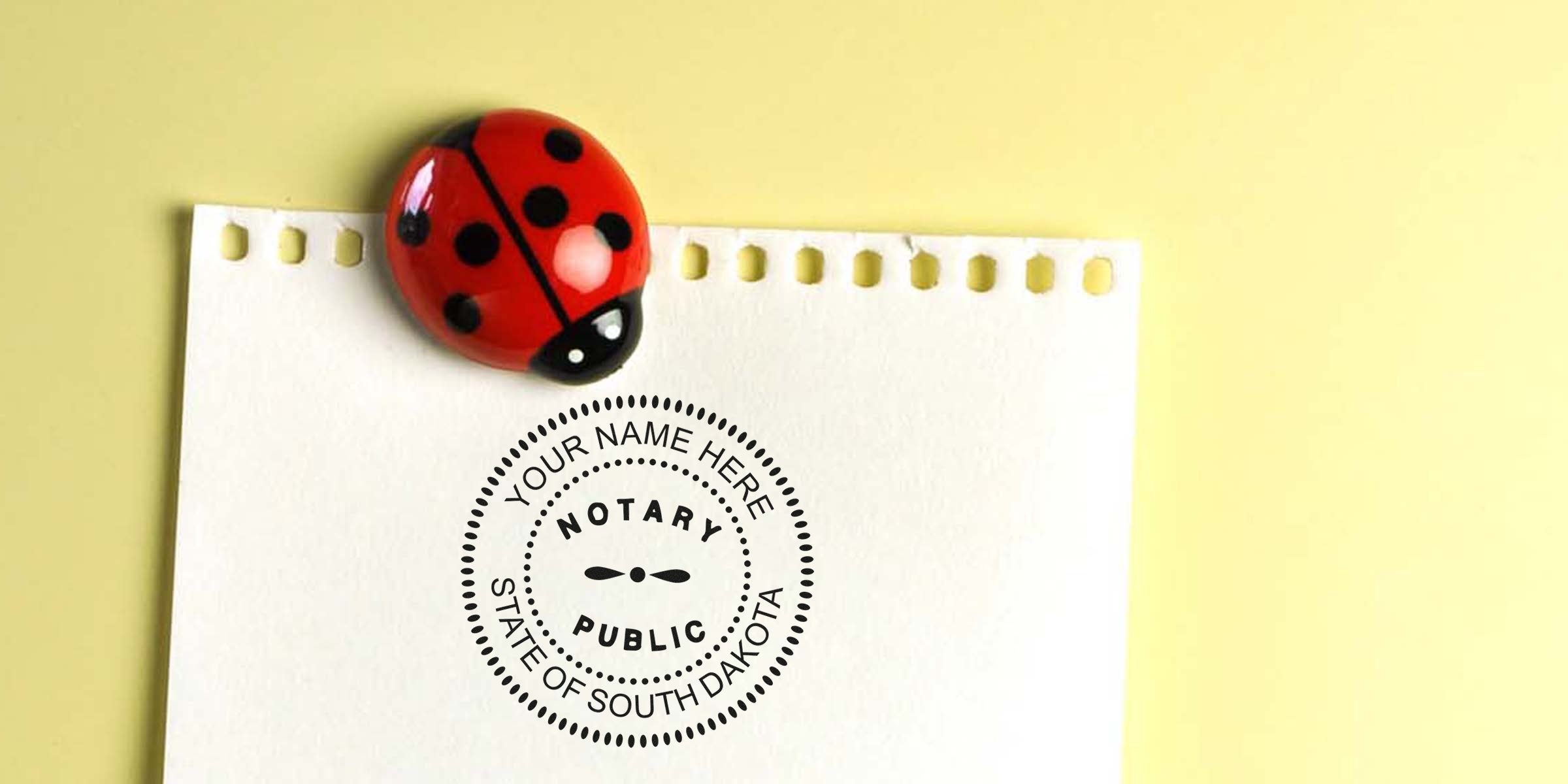 South Dakota notary seal stamped on paper with ladybug magnet, displaying notary seal expiration info.
