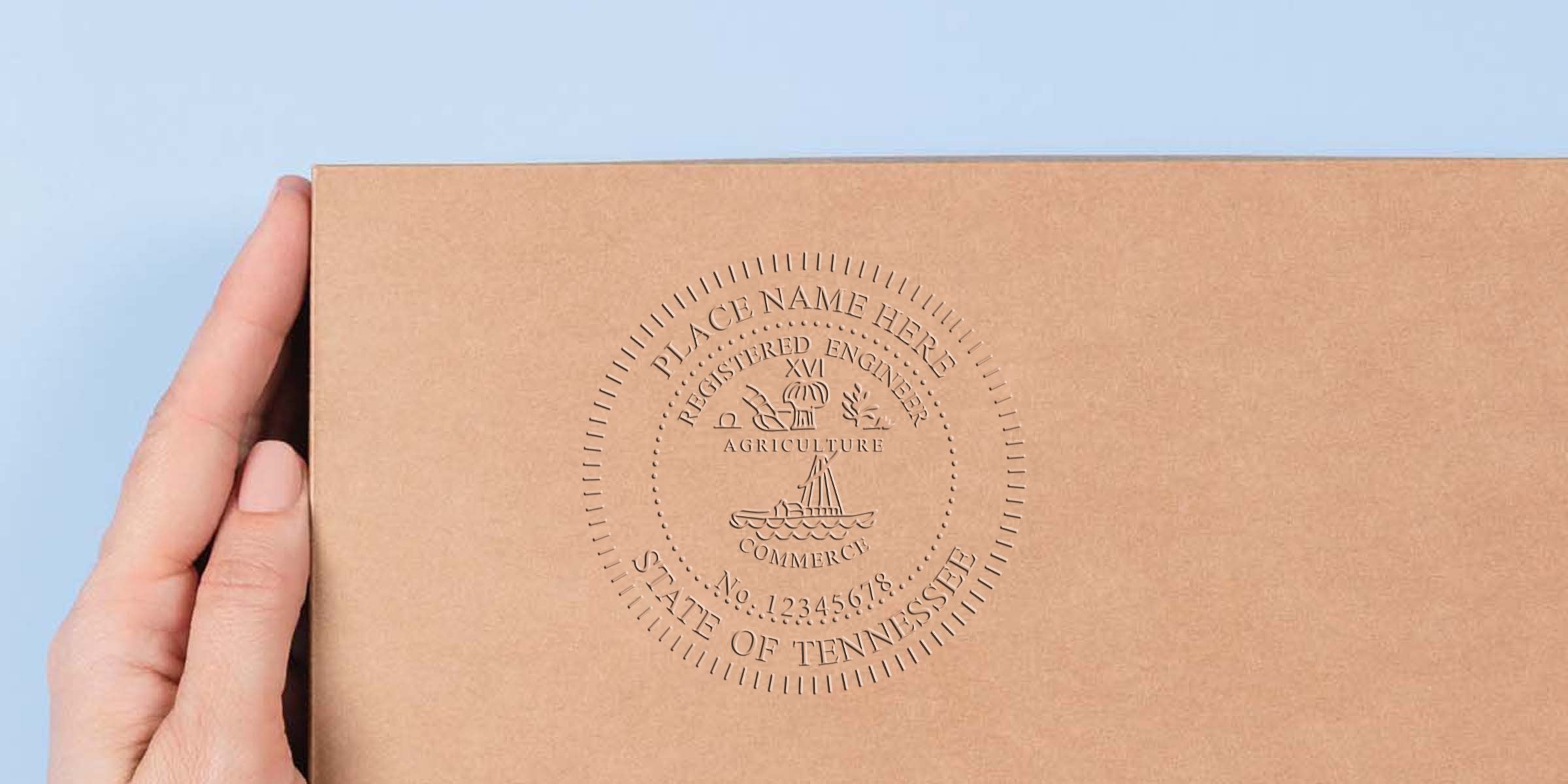 Hand holding brown cardboard box with embossed Tennessee engineering stamp and state seal, meeting all engineering stamp requirements.
