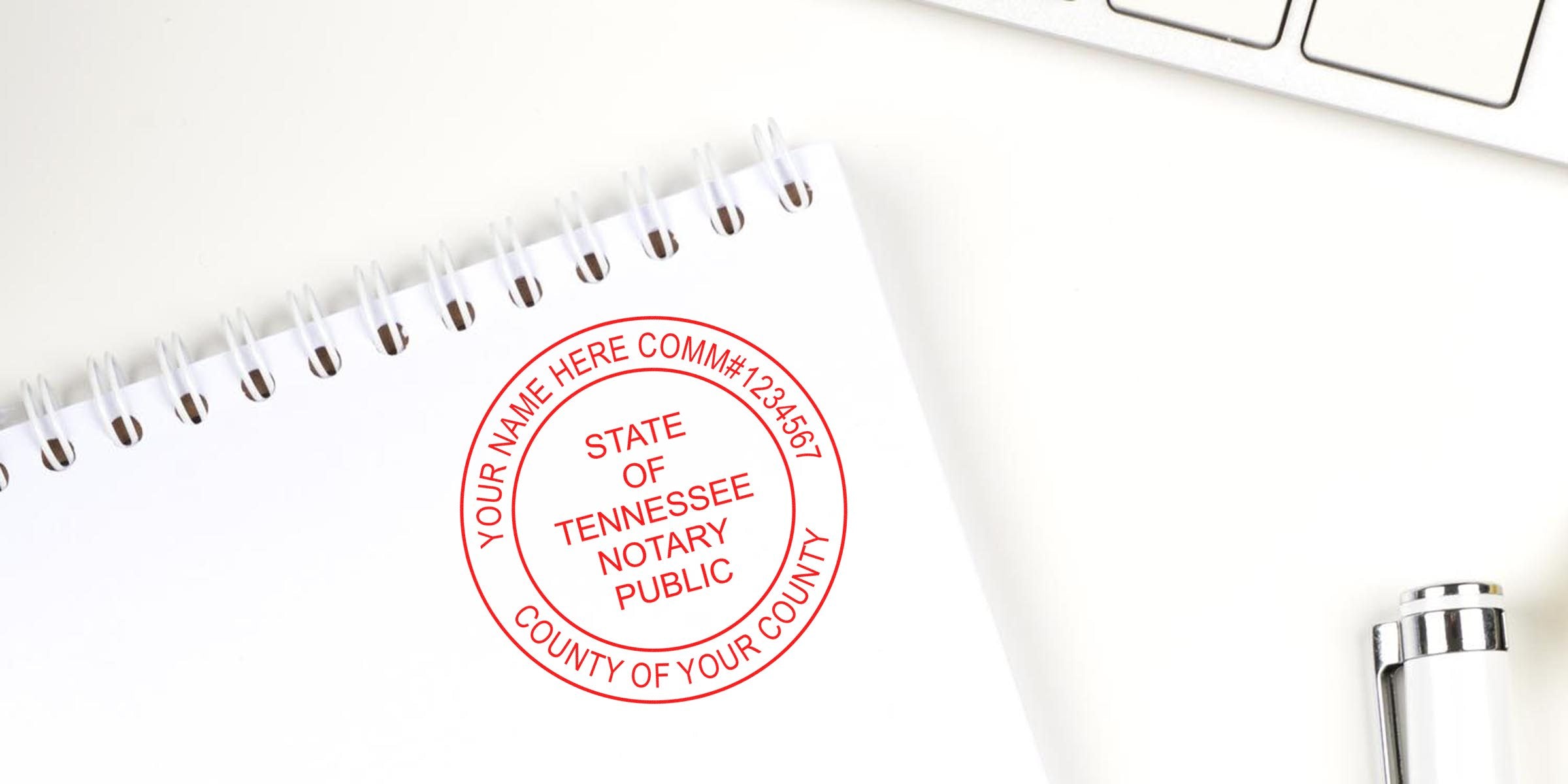 Tennessee Notary Public stamp on a white spiral notebook with a silver pen and keyboard, showing Tennessee Notary Public stamp requirements.
