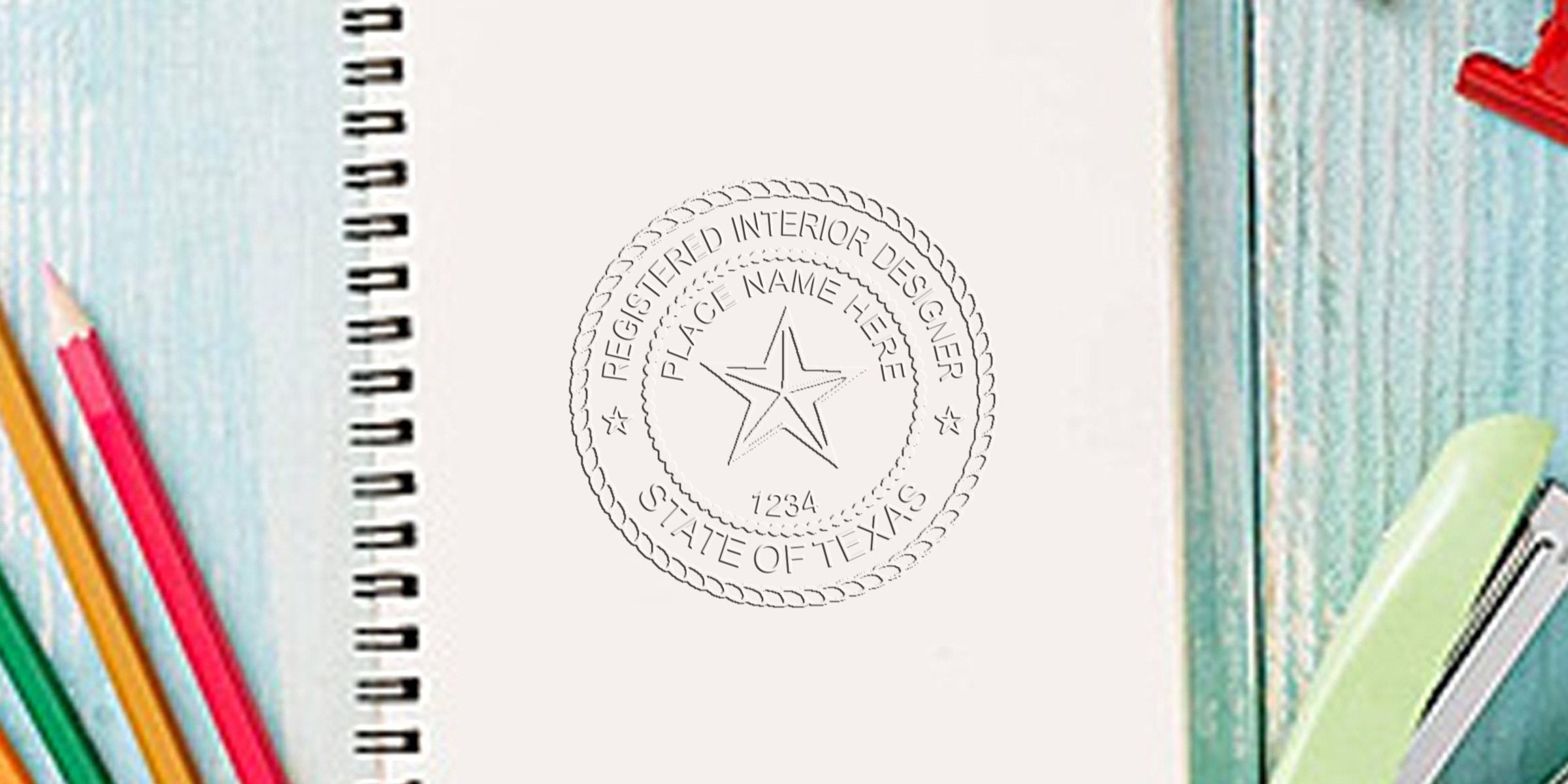 Notebook with Texas interior designer seal and colored pencils on wooden table for design certification.