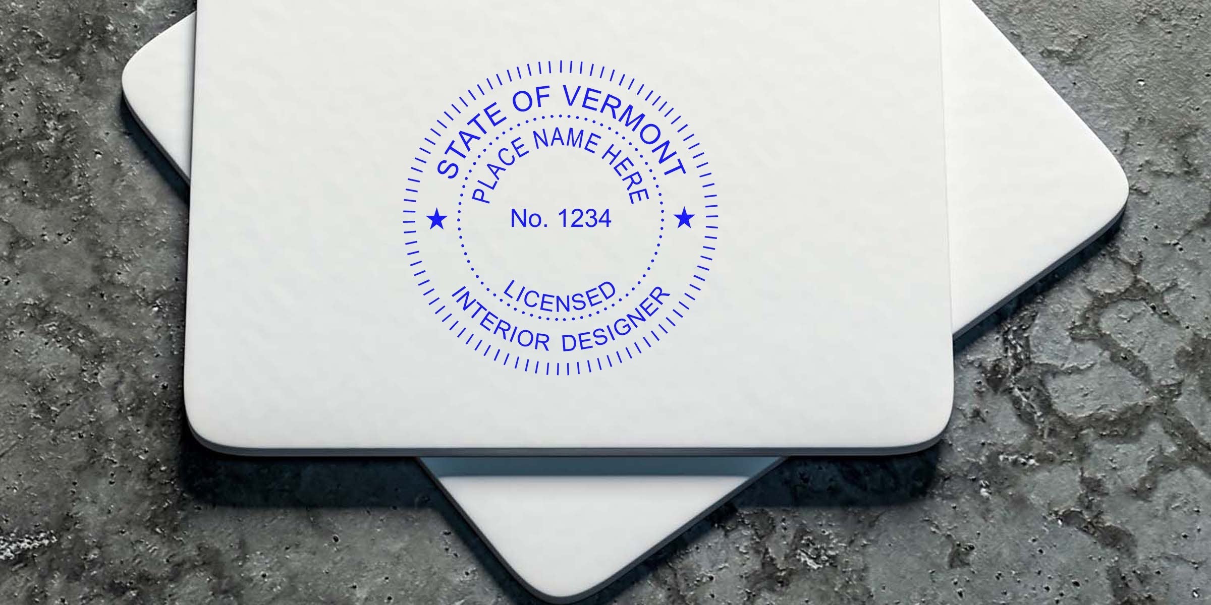Licensed Vermont interior designer stamp on white business cards displayed on textured concrete, highlighting seal maker services.