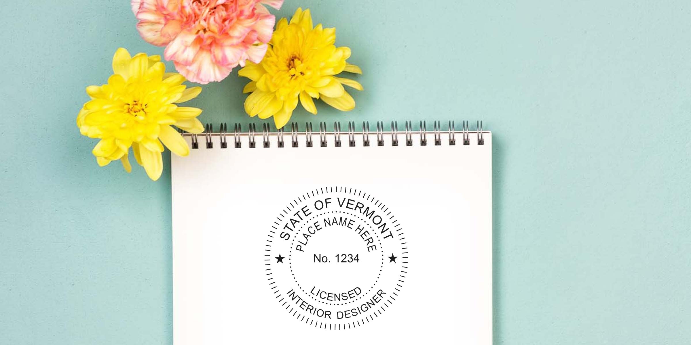 Vermont interior designer license stamp on notebook with yellow and pink flowers on blue background, showing Vermont interior design stamp requirements.