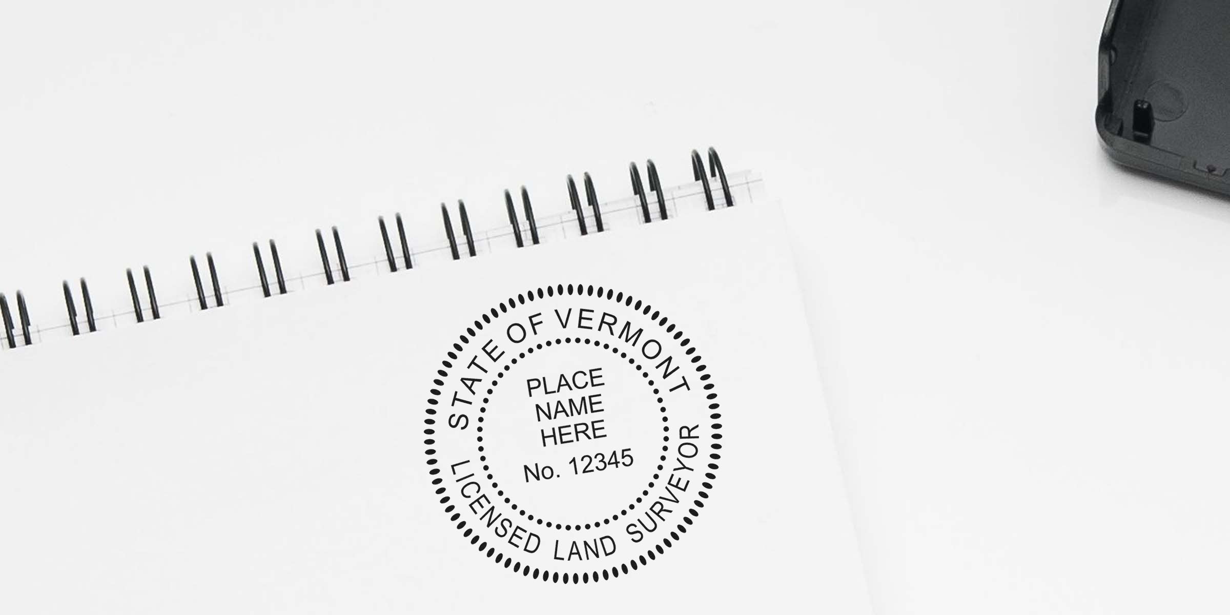 Vermont land surveyor stamp on white spiral notebook with official survey documentation and online certification details.