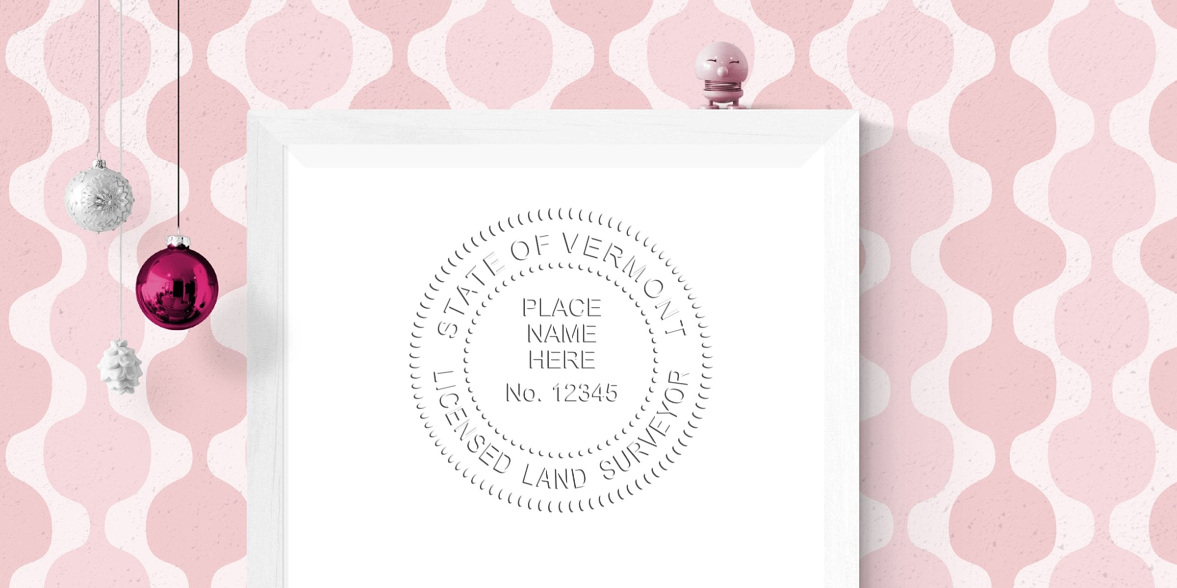 Vermont licensed land surveyor embossed seal on white paper with pink decorative background and hanging Christmas ornaments, featuring Vermont surveyor stamp meeting size guidelines.