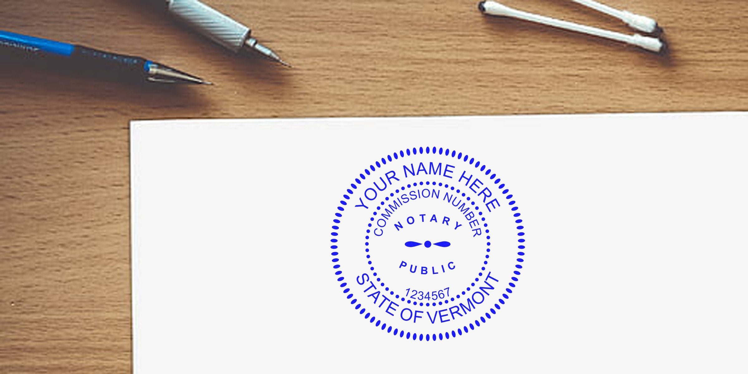 Vermont notary stamp on white paper with pens and cotton swabs on wooden desk, showing a notary public seal; purchase Vermont notary stamp.