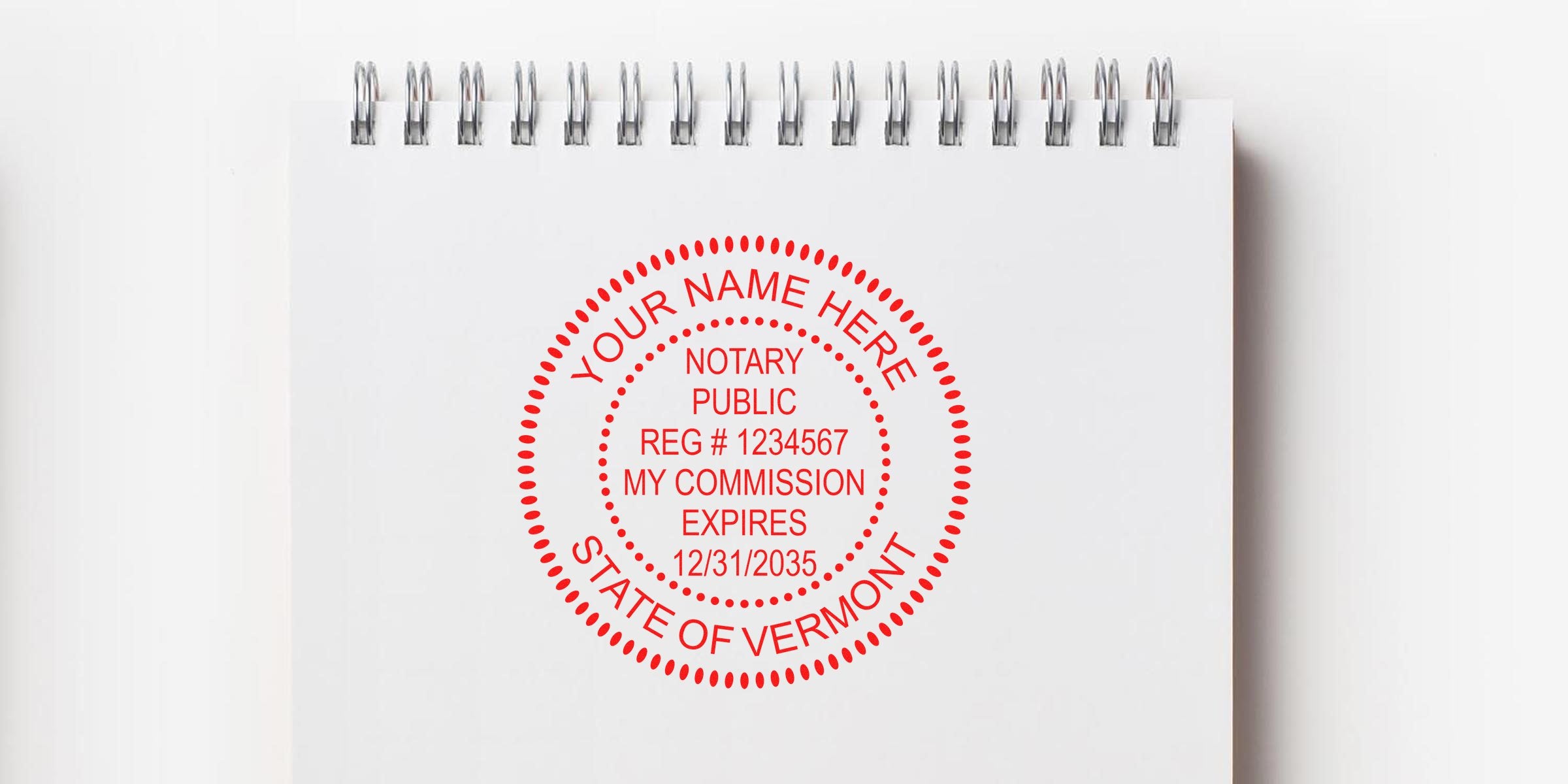 Custom red Vermont notary stamp with commission expiration date on white spiral notebook, featuring official Vermont seal; buy your notary stamp online today.