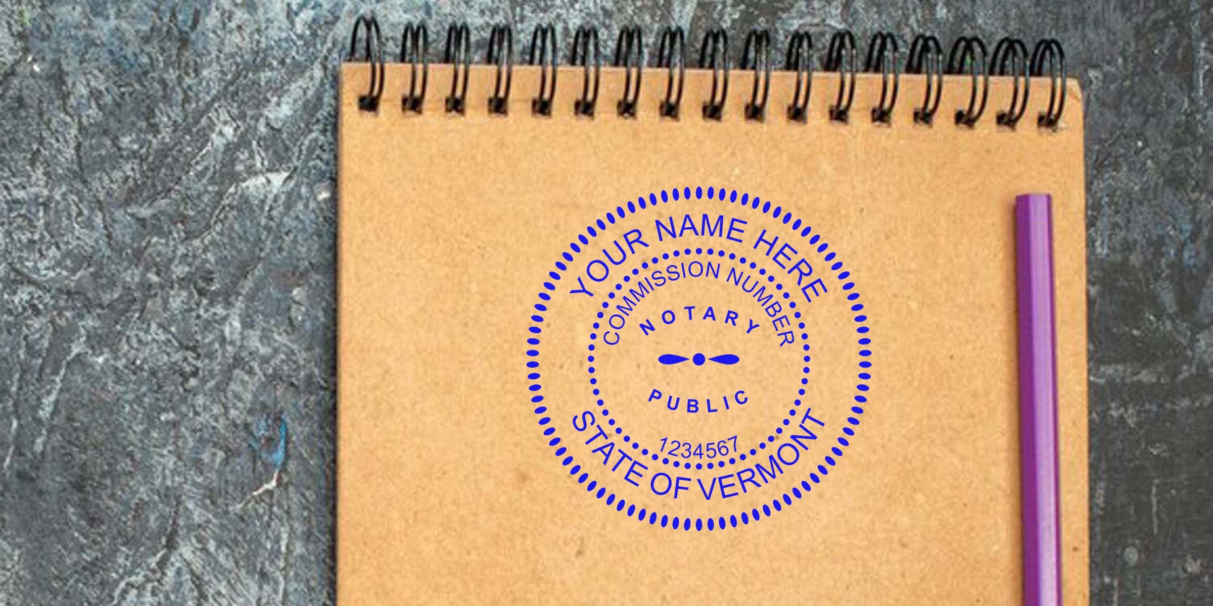 Custom Vermont notary stamp on brown spiral notebook with purple pen on gray textured surface, highlighting VT notary supplies and public notary essentials.