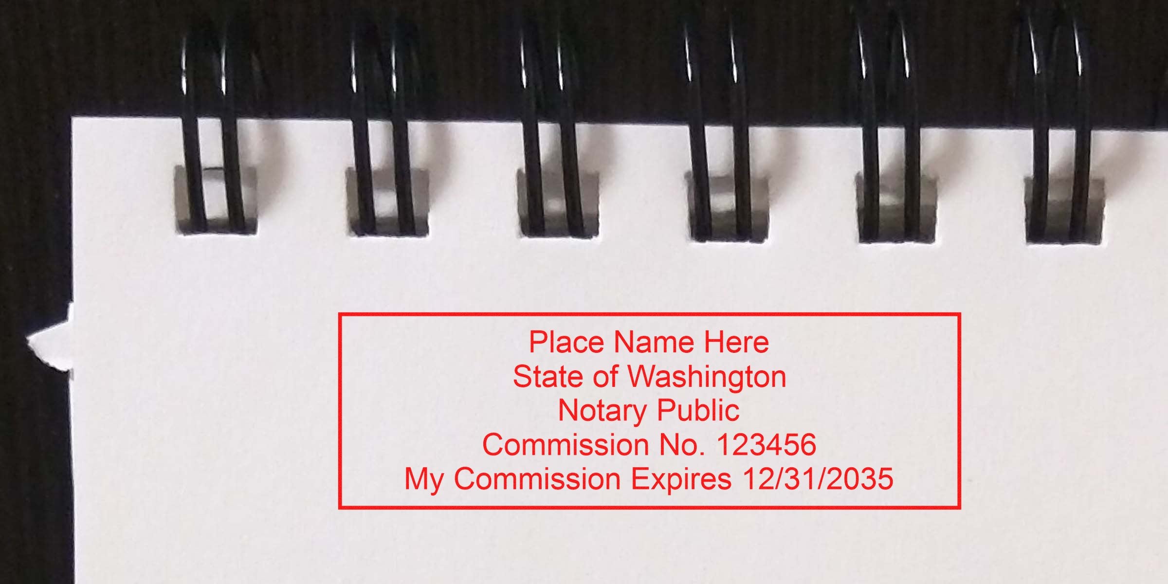 Notary public commission stamp on spiral notebook paper showing Washington state commission number and expiration date, with essential Washington notary supplies and tools.