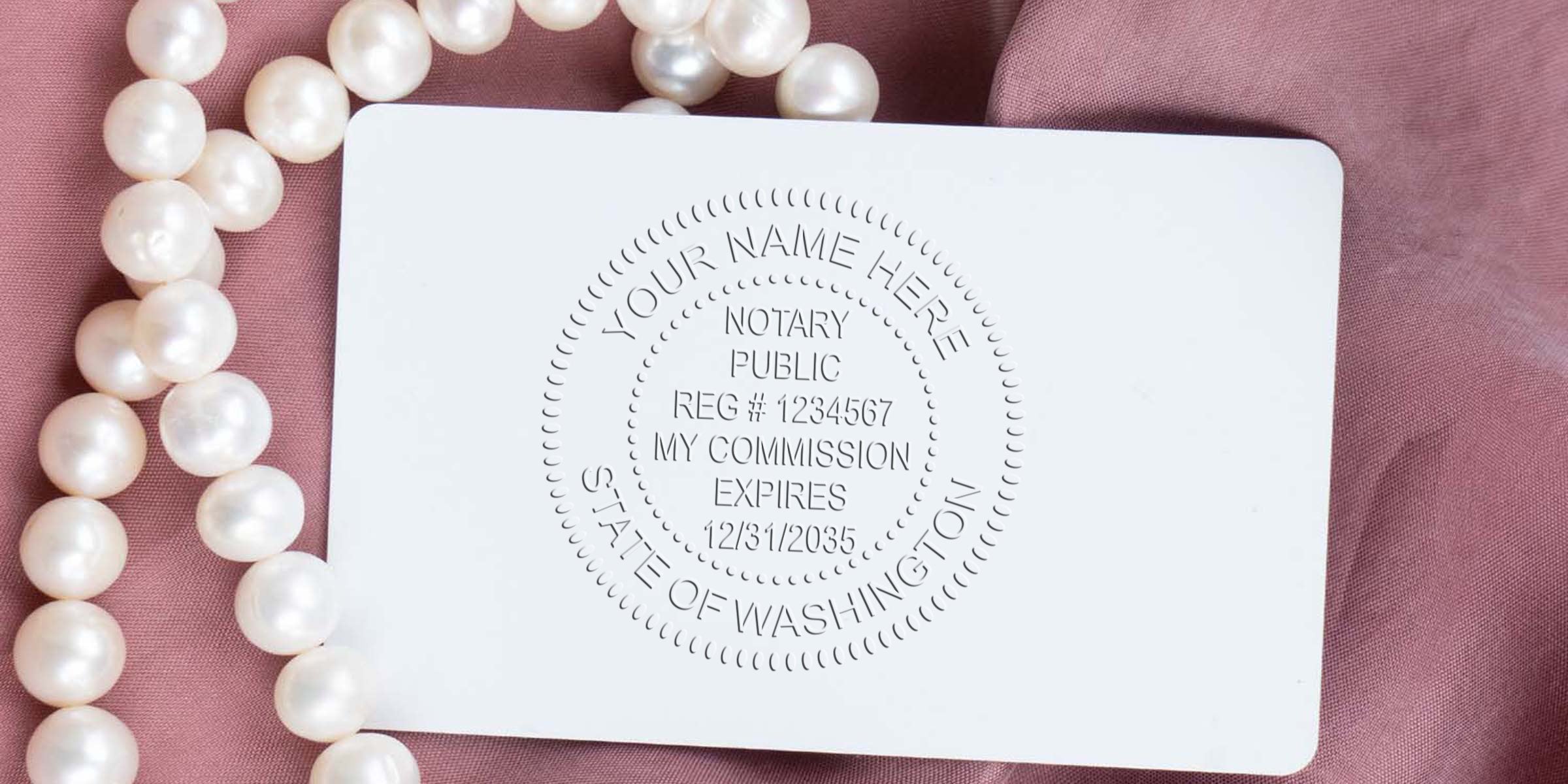 Washington Notary Public embossing seal on white card with pearl necklace on pink fabric, showing how to become a Notary in Washington.