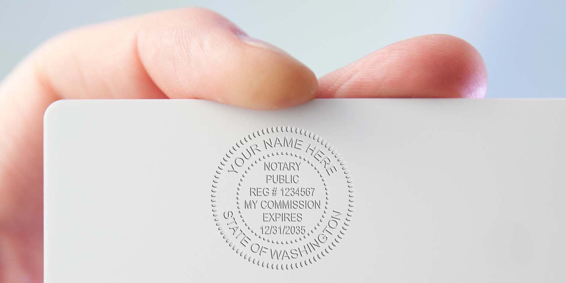 Hand holding white card with Washington notary stamp, showing notary seal and commission expiration date, featuring top Washington notary supplies.