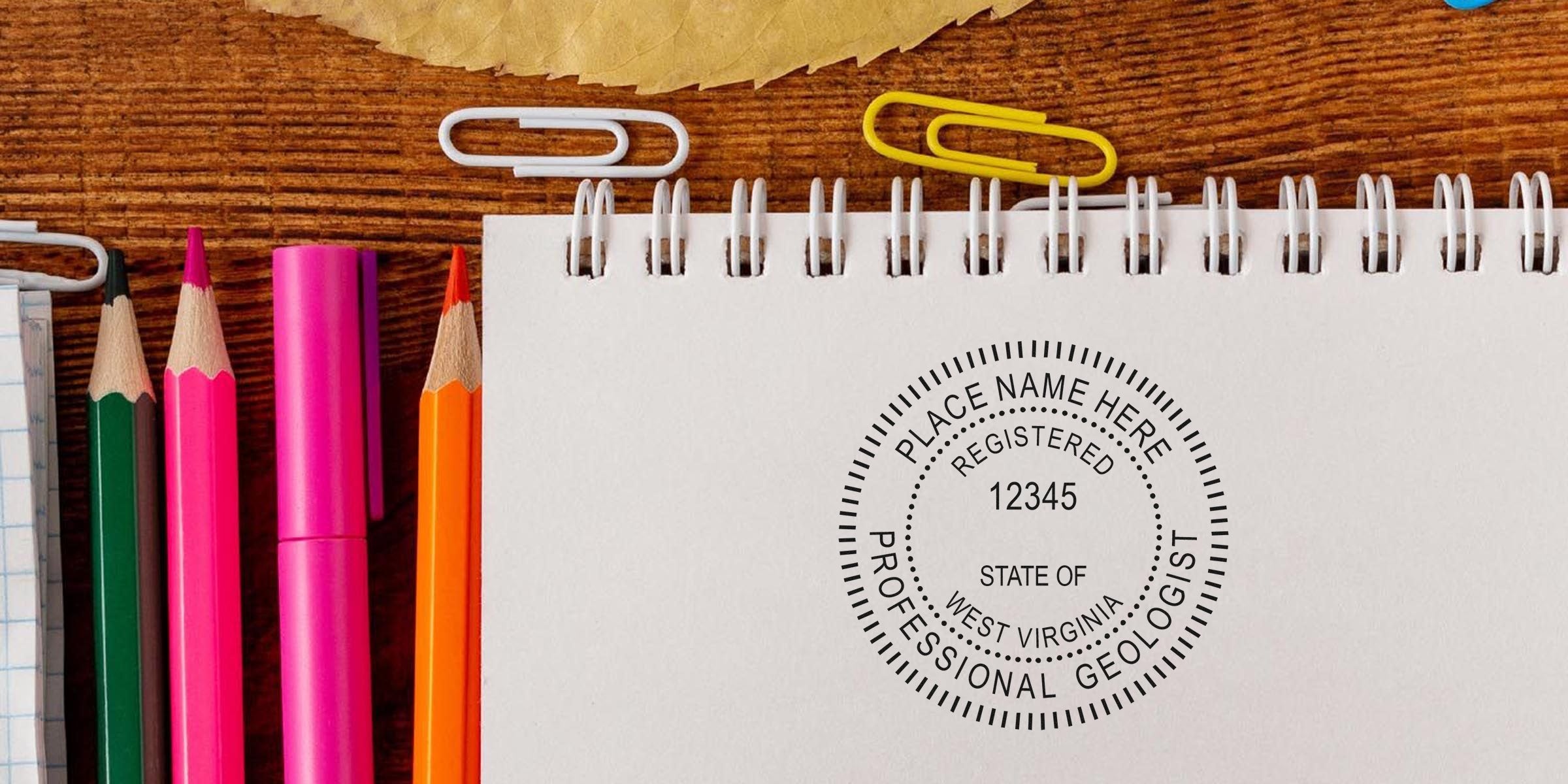 West Virginia Geologist stamp on notebook with colored pencils and paper clips on wooden desk, symbolizing Professional Geologist Certification.