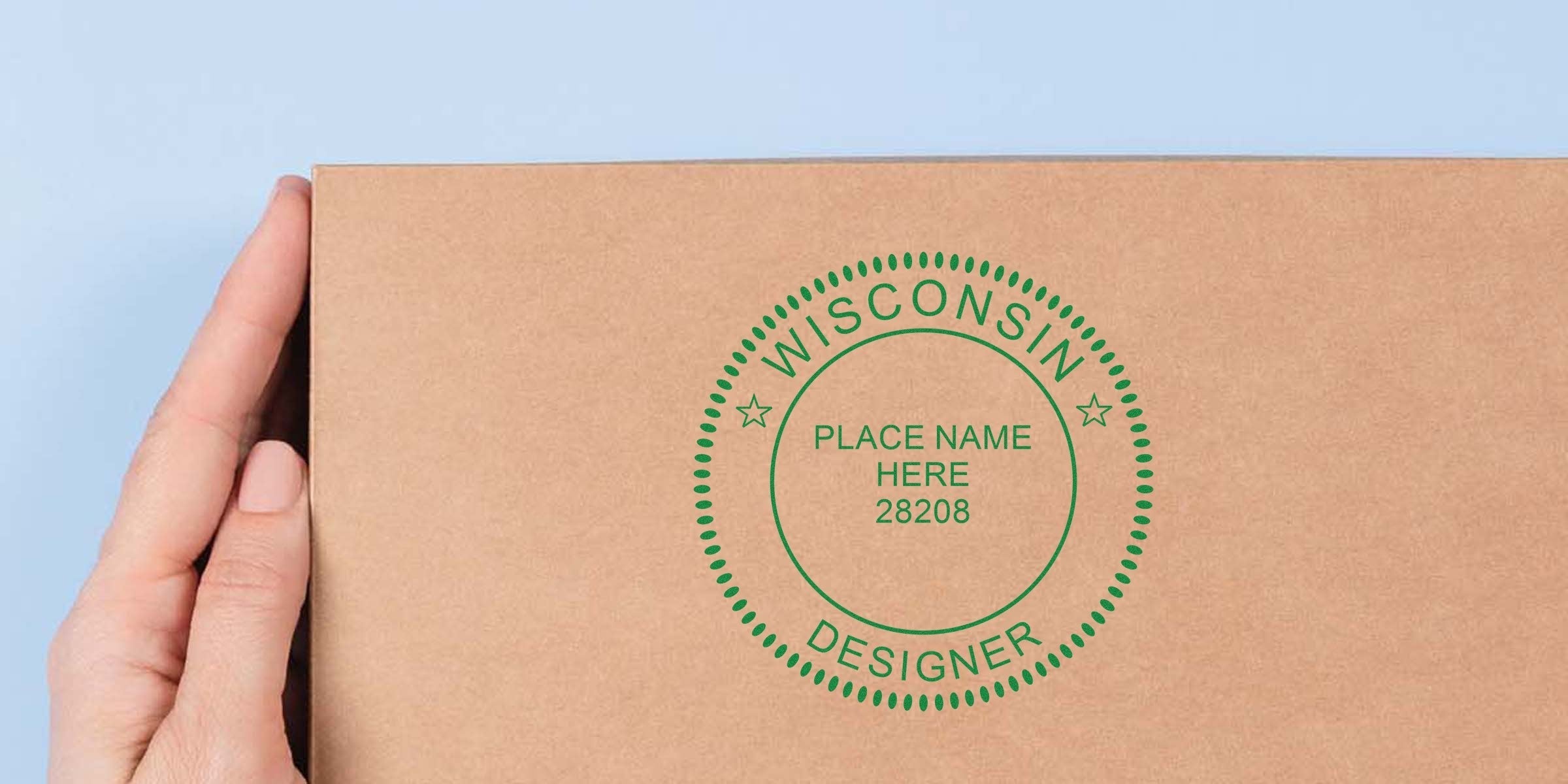 Hand holding a cardboard box with a custom Wisconsin interior designer seal, personalized with place name and zip code; ideal for packaging and shipping, includes interior designer embosser guide.