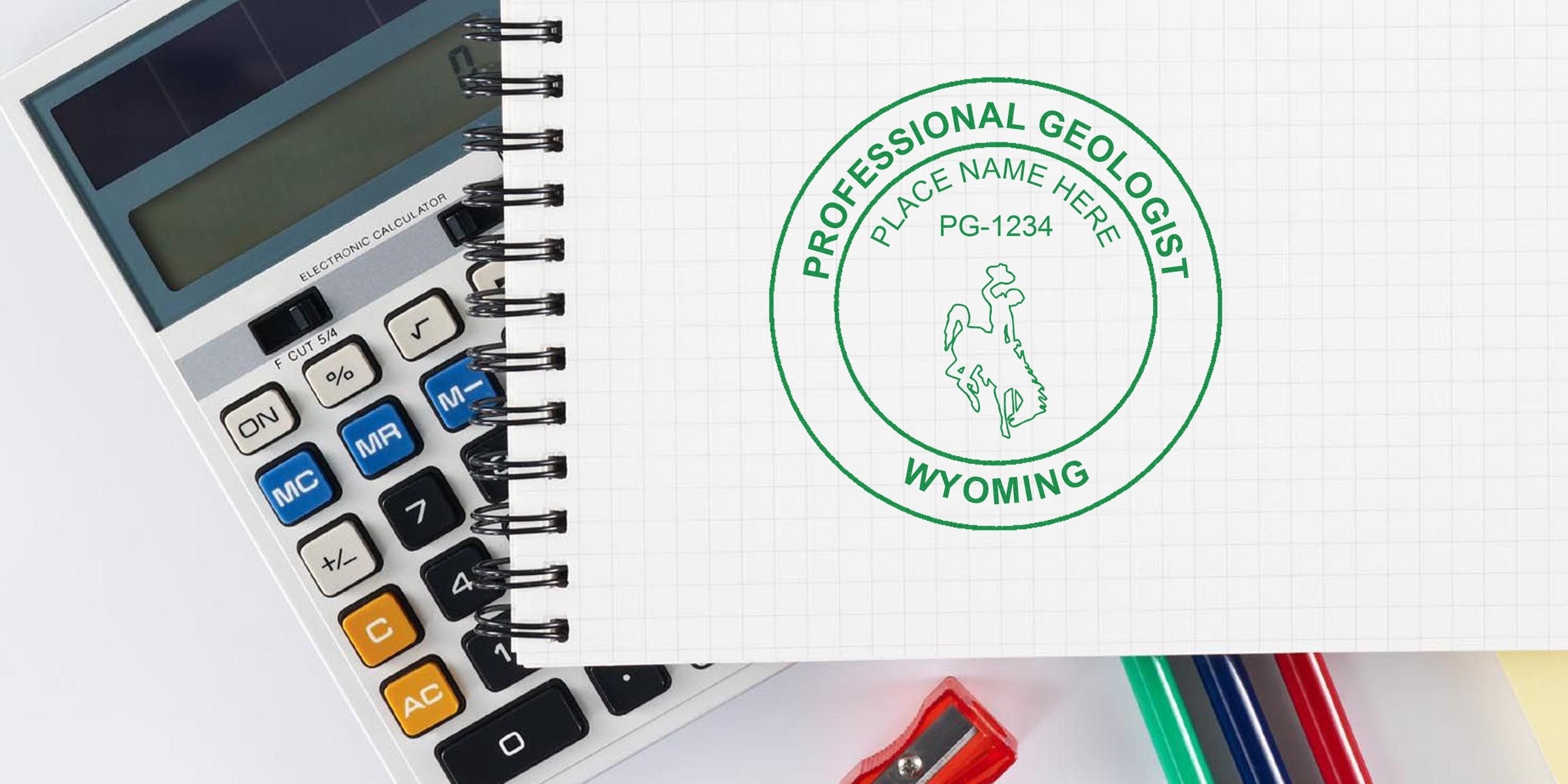 Geologist stamps "Wyoming" on notebook with calculator and stationery, showcasing Geological Design Wyoming elements.