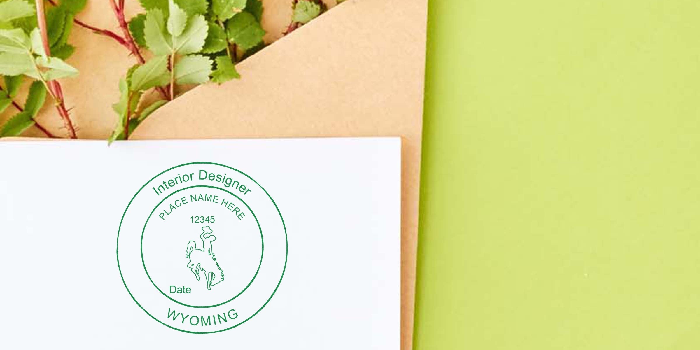 Wyoming interior designer logo stamp on white envelope with green leaves and kraft paper background, highlighting Wyoming Interior Designer Stamp Laws and Design Regulations.