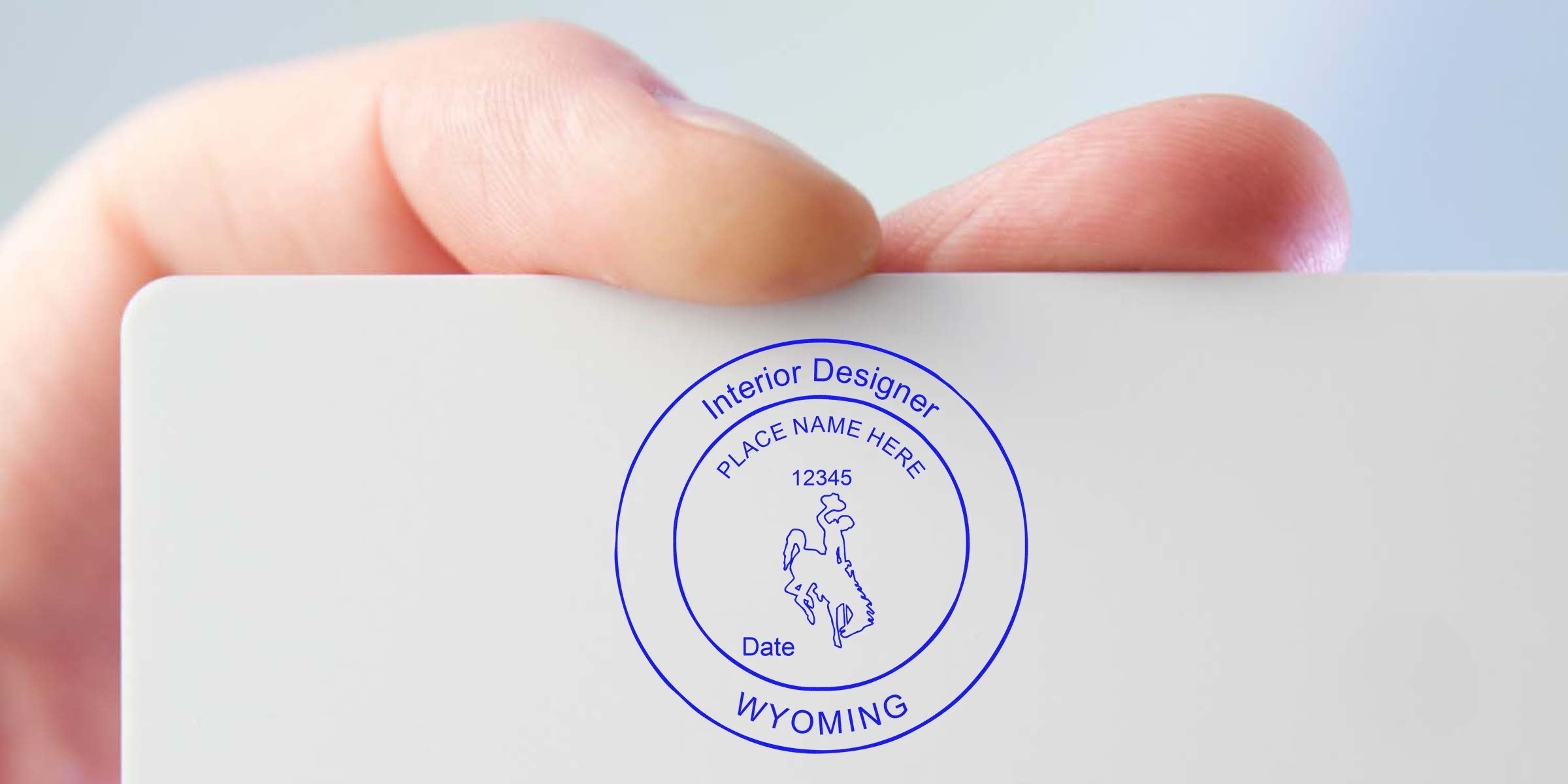 Hand holds business card with Wyoming interior designer stamp and Seal Specs design.