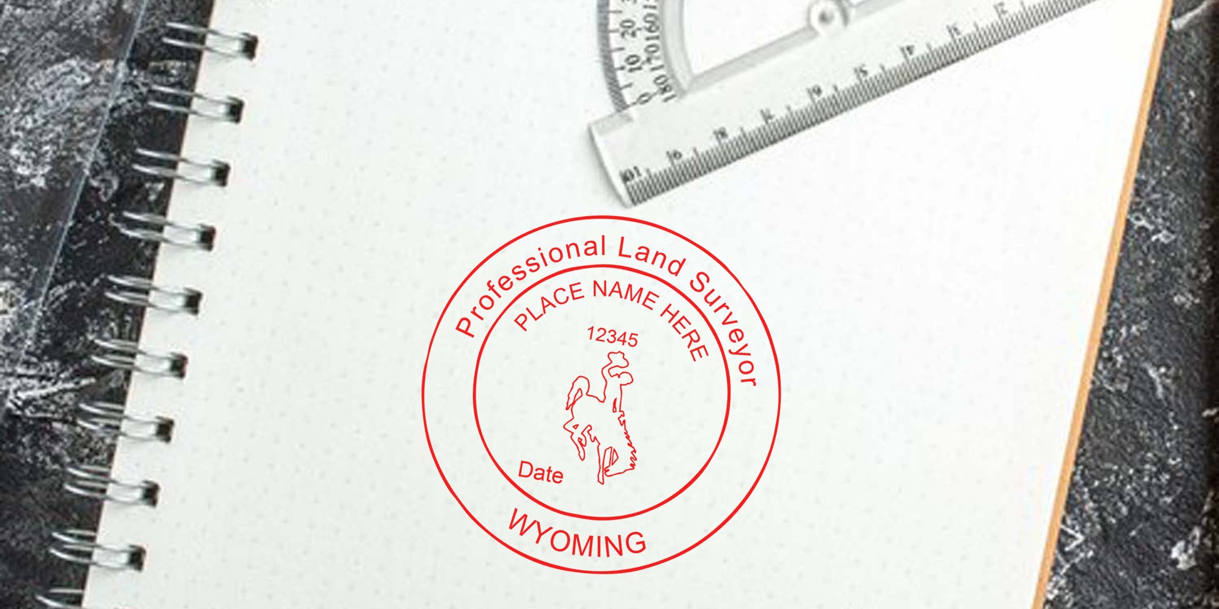 Wyoming land surveyor stamp on a notebook with protractor and ruler, highlighting Wyoming land surveyor regulations.