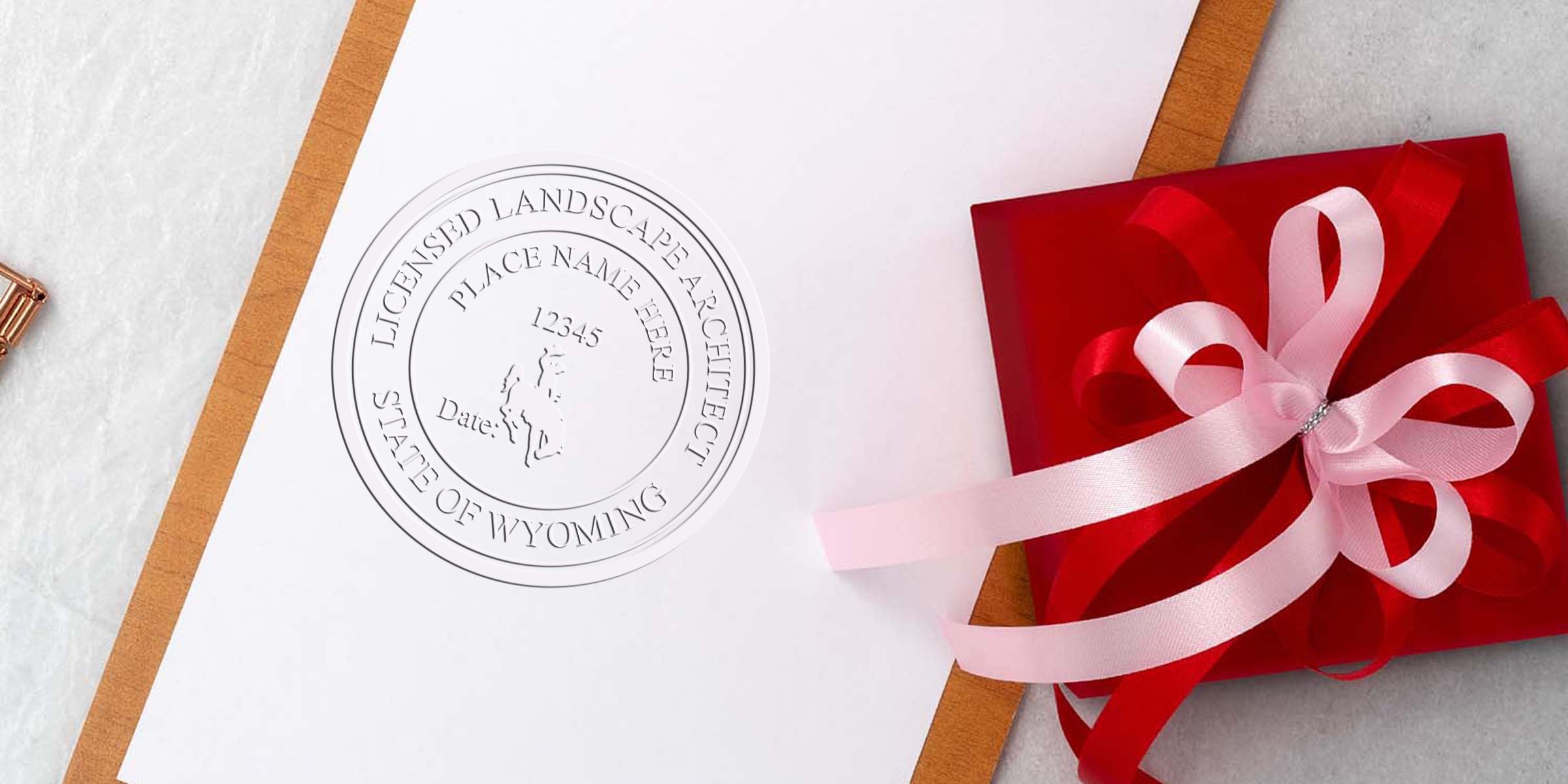 Licensed landscape architect seal on white paper next to a red gift box with pink ribbon on marble, featuring a Wyoming stamp design inspired by Wyoming postage stamps.